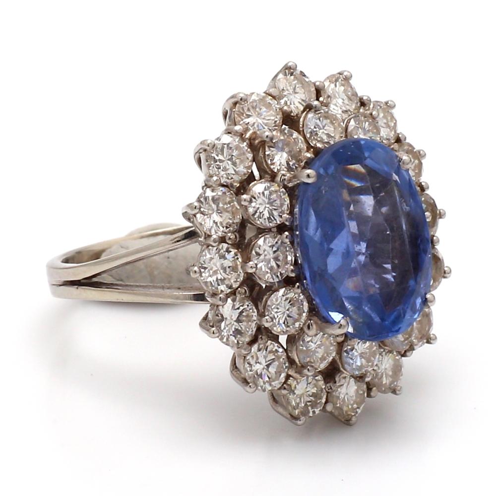 18K white gold, cocktail ring.  Center stone is one (1) oval cut, no heat, sapphire weighing 6.00ct. Sapphire is accompanied by an AGL Prestige Gemstone Report #1113440. Sapphire is surrounded by twenty-eight (28) round brilliant cut diamonds