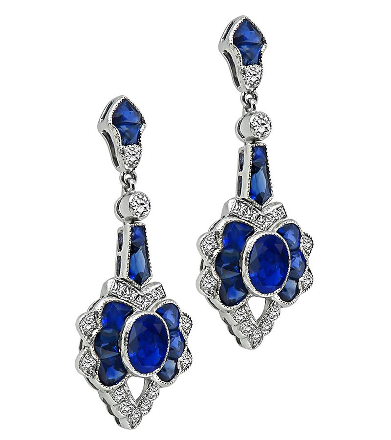This is a stunning pair of 18k white gold earrings. The earrings feature oval, fan and trapezoid cut sapphires that weigh approximately 6.00ct. The sapphires are accentuated by sparkling round and princess cut diamonds that weigh approximately