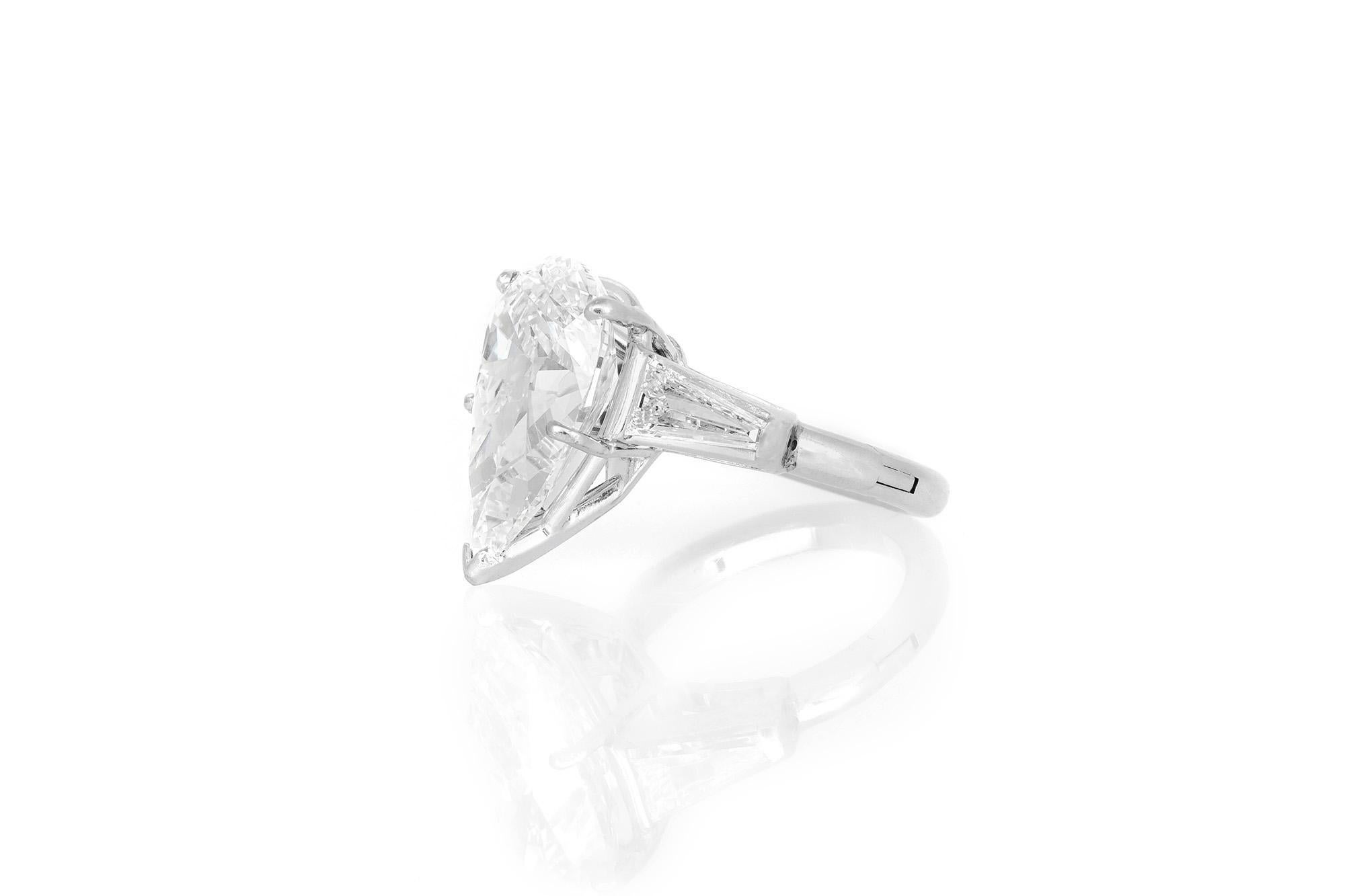 Finely crafted in platinum with a GIA certified Pear-Shaped Diamond at the center weighing 6.02 carats, H color, VS1 clarity, GIA #2125799522.
The ring features 2 accenting Tapered Baguette cut Diamonds, and an adjustable mechanism that widens to