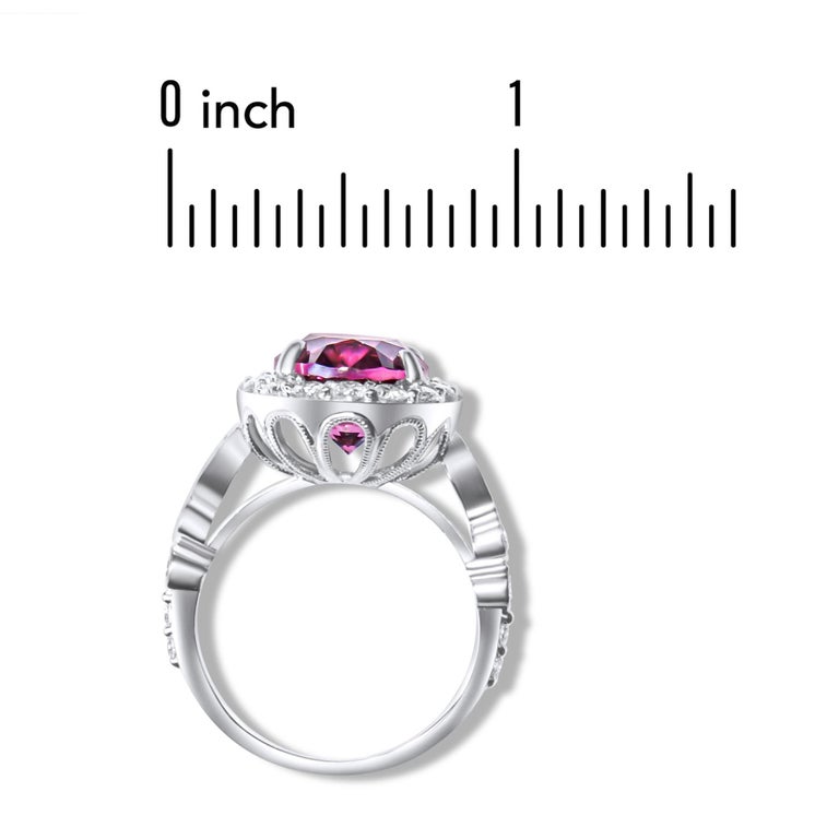This ring has a vibrant oval cut Raspberry Garnet center (6.04 carats), surrounded by a halo of round white diamonds. Additional diamonds, including two pear shapes along the shank, bring the total diamond weight to 1.20 carats. Set in 14k White