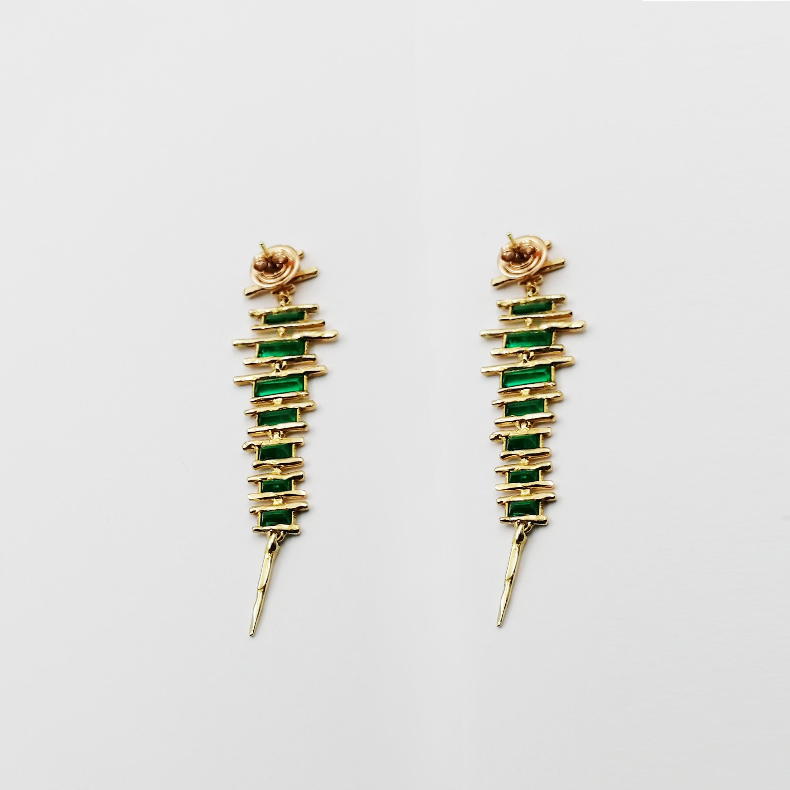 Exceptionally artistic in their design, these earrings convey the appeal of an artwork painted to embellish the earlobe and appear like brush strokes of gold underlining the alluring beauty and captivating color of green emeralds. The dynamic ductus