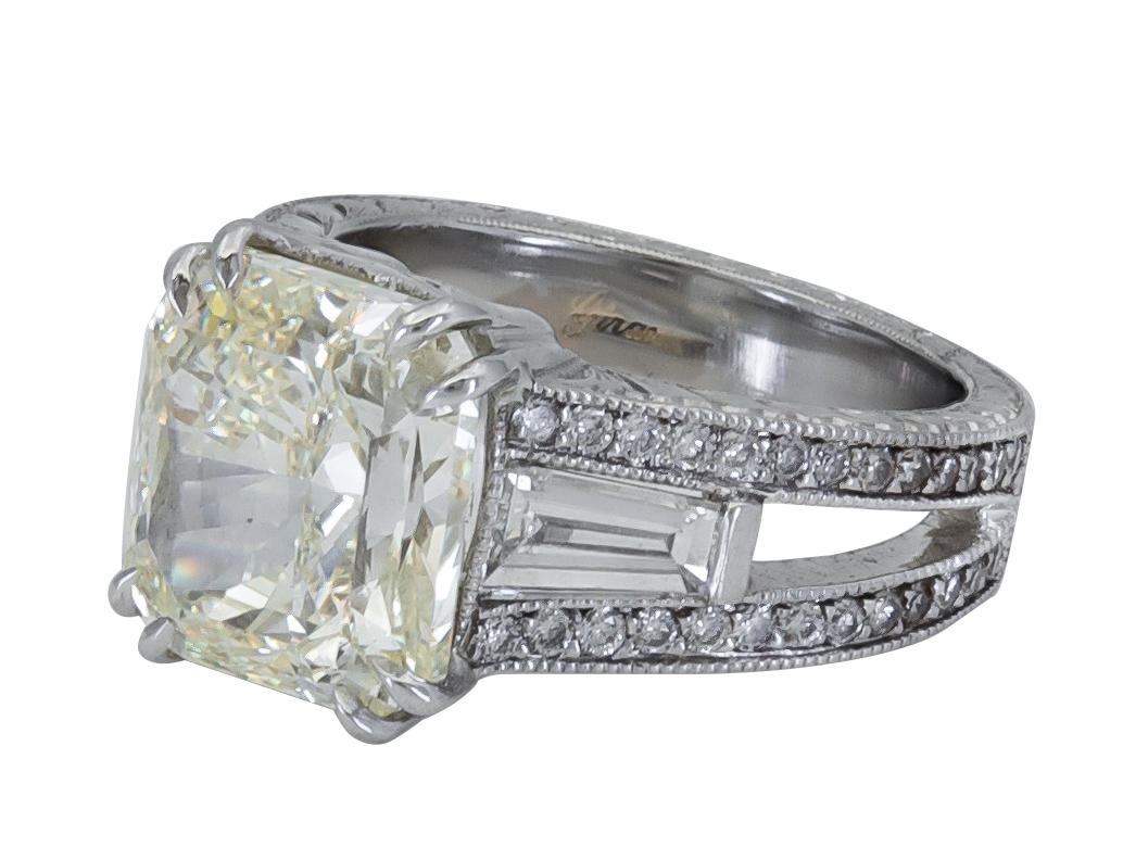 Features a color-rich yellow diamond, flanked by tapered baguette diamonds on either side. The side diamonds are set in-between a row of round brilliant diamonds set in polished platinum.
Yellow diamond weigh 6.07 carats.
Accent diamonds weigh 1.40