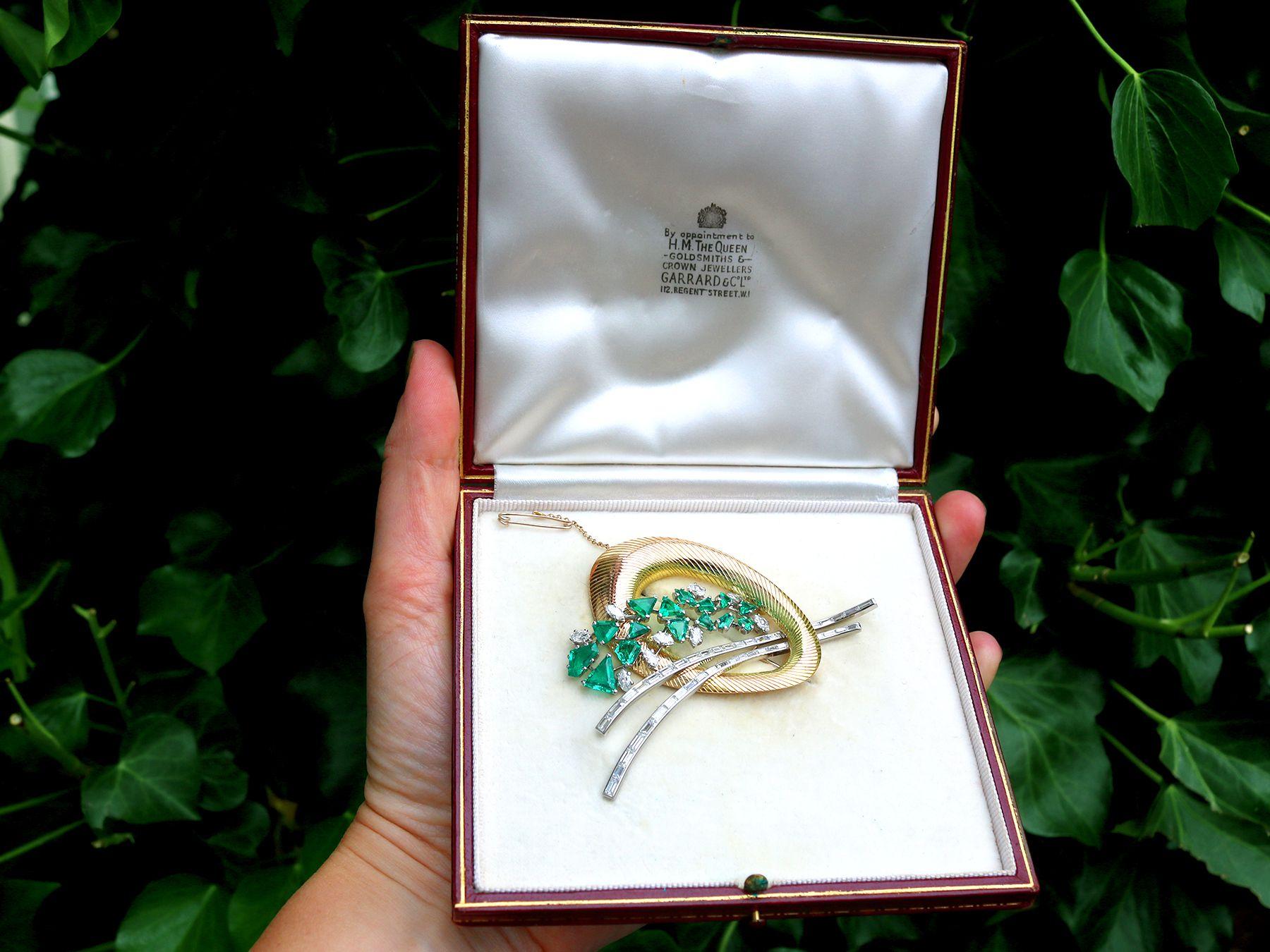 A stunning, fine and impressive, large antique 4.05 carat diamond and 6.07 carat emerald, 18 karat yellow gold and platinum Art Deco style brooch made by Garrards & Co Ltd; part of our diverse antique boxed jewelry and estate jewelry