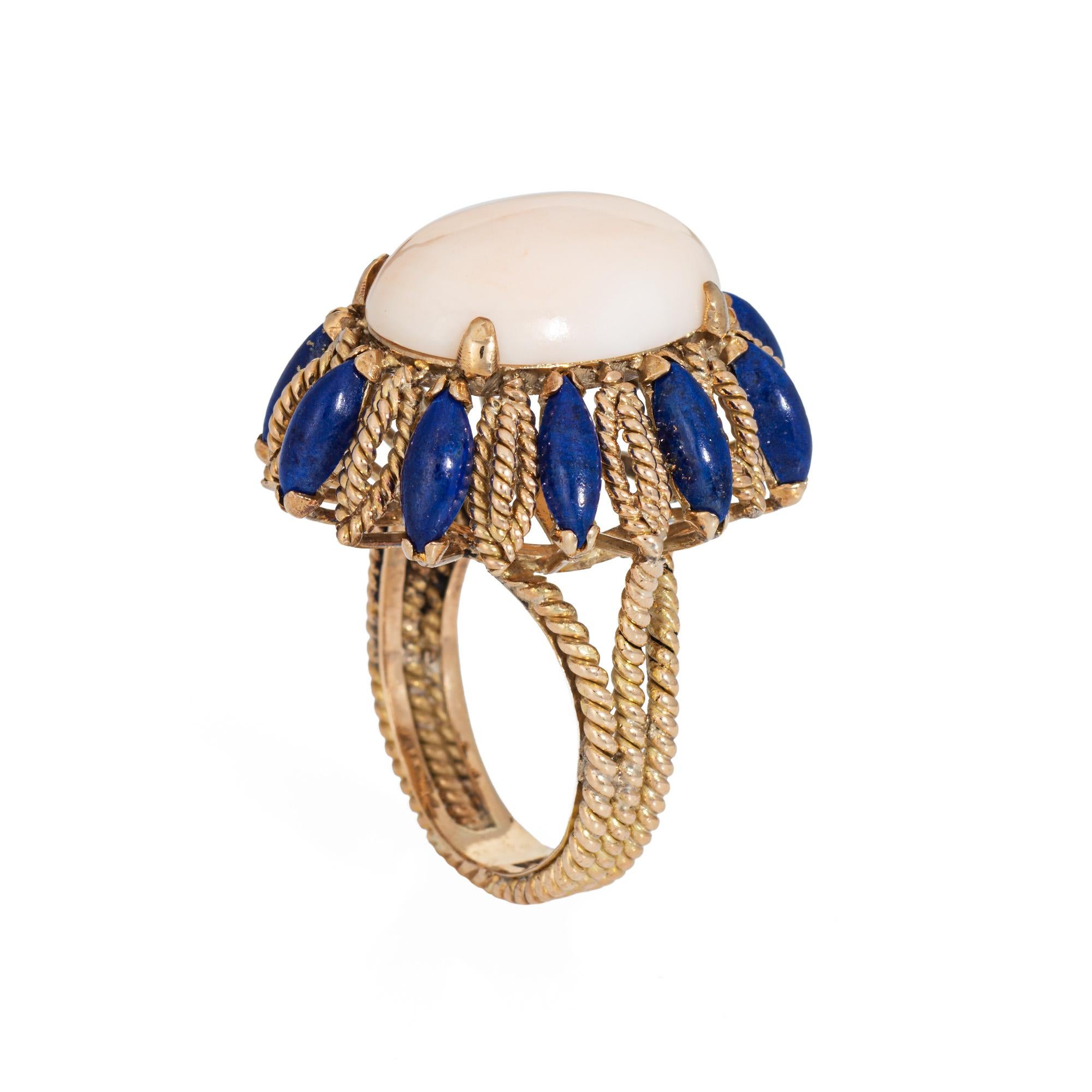 Stylish vintage angel skin coral & lapis lazuli cocktail ring (circa 1960s) crafted in 14 karat yellow gold. 

Coral cabochon measures 18mm x 13mm. Marquise cut lapis lazuli measures 6mm x 3mm. The coral is in good condition with a small chip