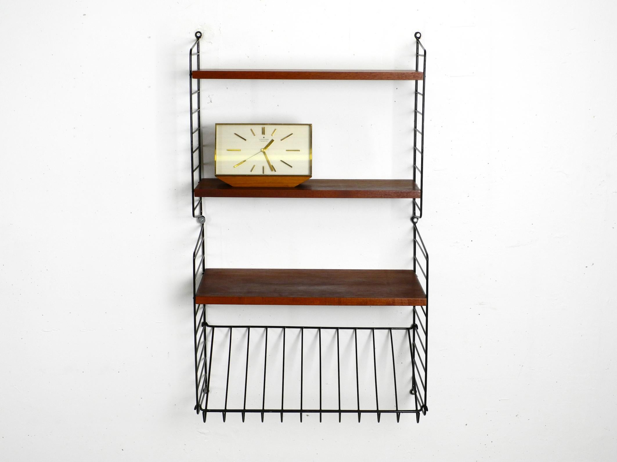 Original 1960s Nisse Strinning wall hanging shelf.
Three narrow solid wood floors with dark teak veneer.
Two ladders are 20 cm deep and have two 20 cm deep shelves.
Two ladders have a depth of 30 cm and come with one shelf with a depth of 30 cm and