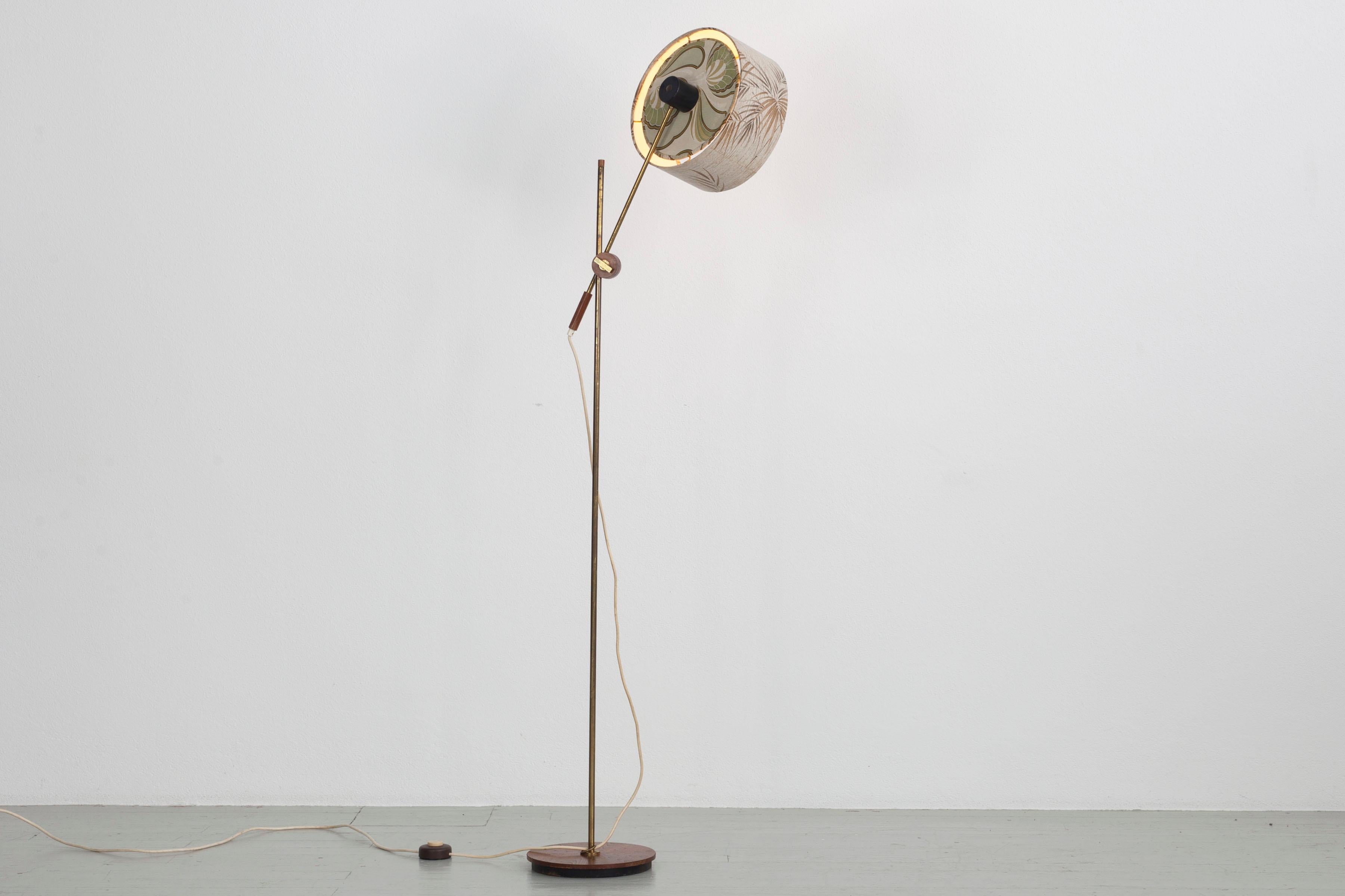 60s Floor lamp with adjustable height and position lampshade. The lampshade is covered with patterned paper inside and outside. The lamp base is made of teak and frame of brass. The lamp has an E27 socket. It is 143cm high and the diameter of the