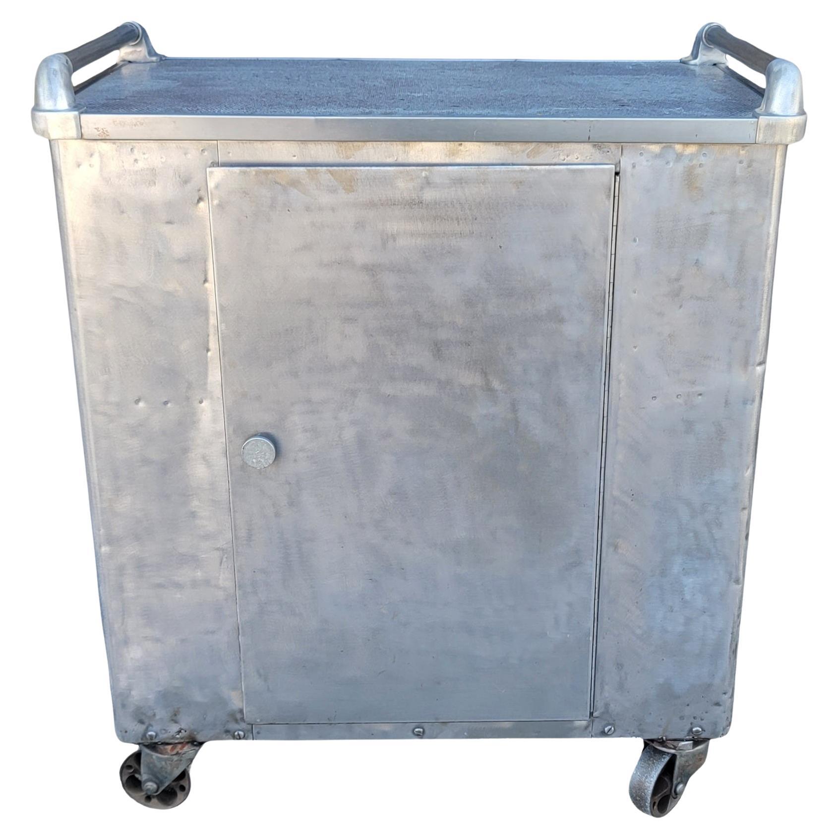 60s Industrial Tanker Style Tol Base Cast Iron Caseium  Cart Trolley. The casters are made from steel to hold the weight of the cast. There is one door with 2 shelves on the interior. The sides have pockets to place items in. Within these pockets