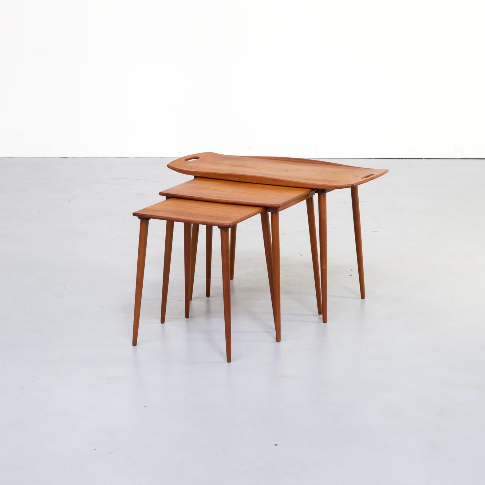 Highly detailed and beautiful teak nesting tables with serving tray handles designed by Jens Quistgaard for Richard Nissen. The sculpted top of the largest table features finger cut-outs at each end, raised edges and slender, tapered legs. A rare