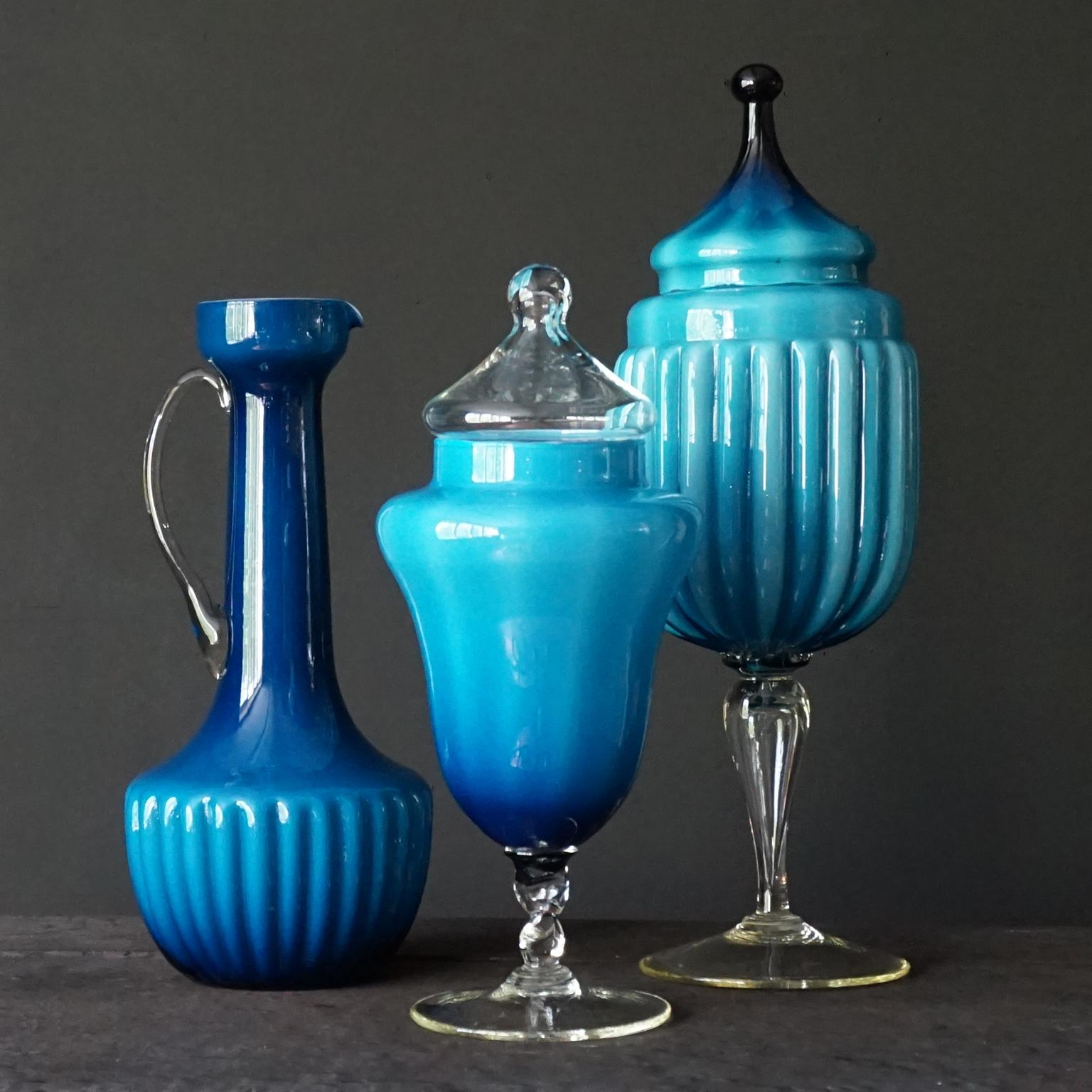 Grazioso set di tre vasi in vetro incamiciato degli anni '60 di Empoli Rossini e Stelvio Opalina Fiorentina. Una brocca alta, un vaso o un decanter e due barattoli per caramelle o barattoli da farmacia. 
In tonalità blu intenso e colori coordinati.