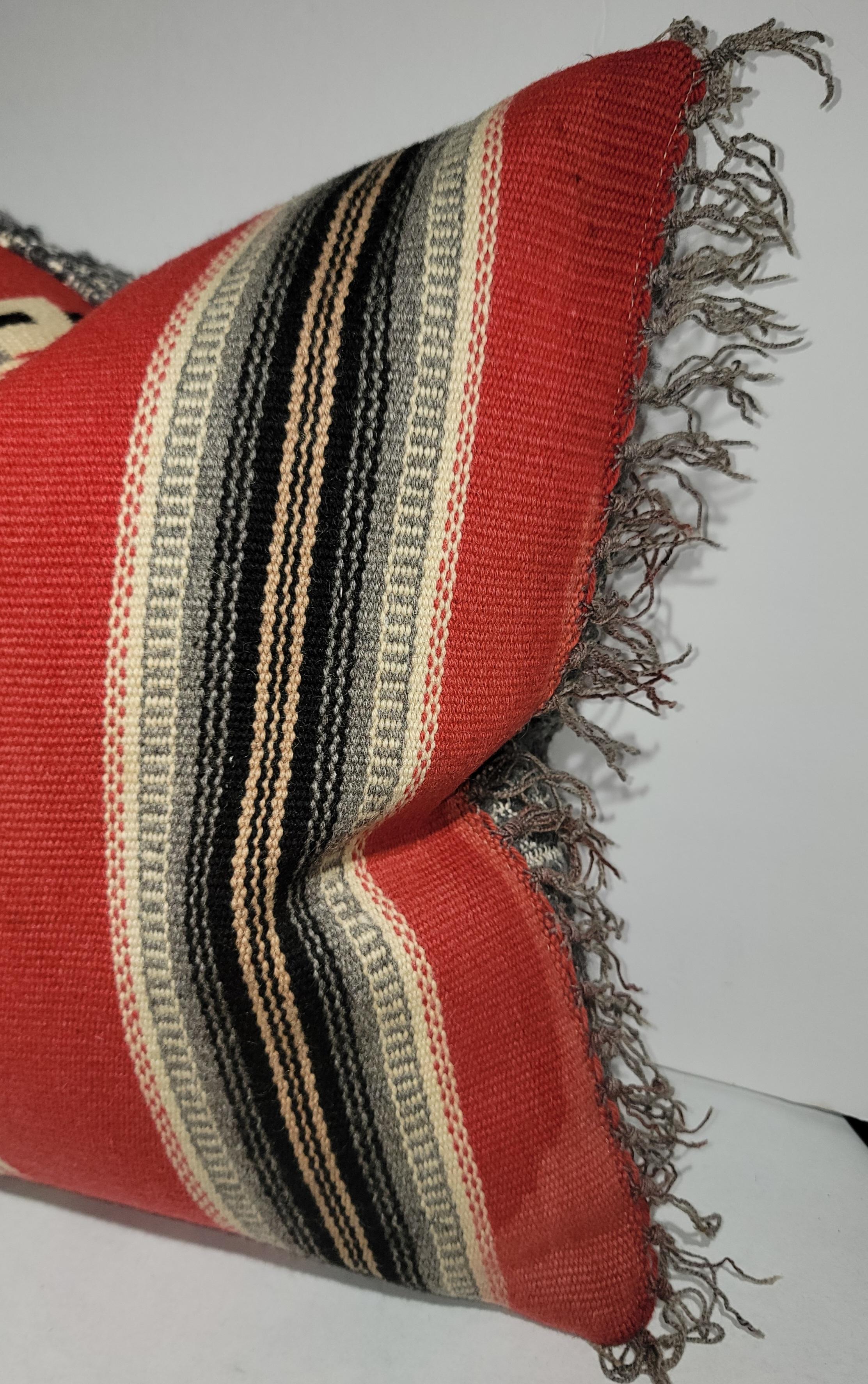 Mexican Indian Wool Serape Pillow with fringe and a wool backing. This All wool pillow has its bright side as well as its neutral side. The reds are highly visible with the grays, dark brown and white color pallet bringing the reds back to a subtle