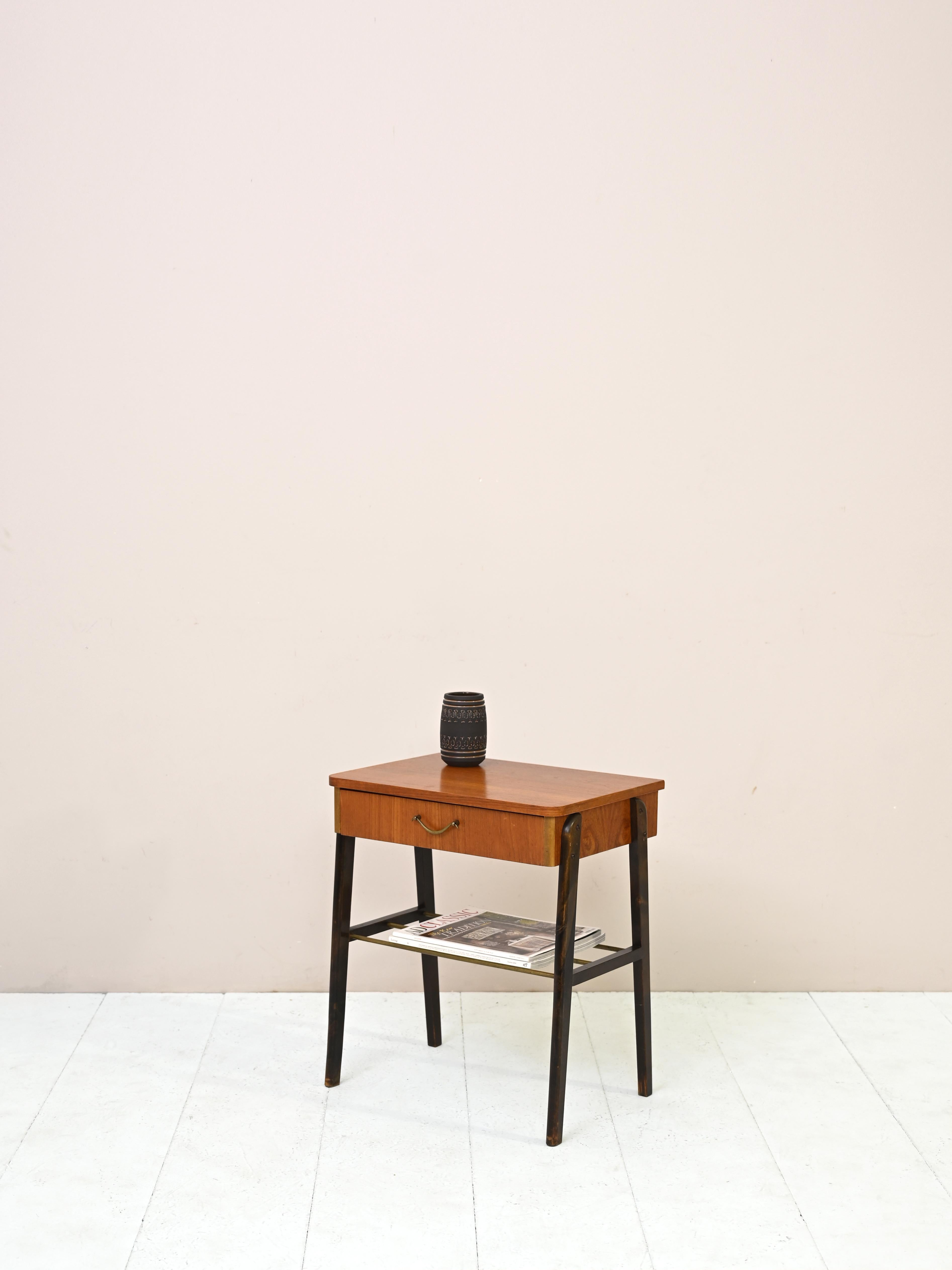 Table de nuit scandinave vintage particulièrement originale.
Un meuble qui se distingue par ses lignes modernes avec une touche rétro. Le dessus est en teck tandis que
les pieds en bois peints donnent du caractère à la structure. La poignée du