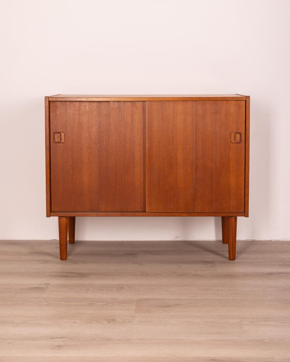 Teak wood sideboard, with two sliding doors, Danish design, 1960s.

CONDITIONS: In good condition, it may show signs of wear given by time.

DIMENSIONS: Height 74 cm; Width 90 cm; Length 42 cm

MATERIALS: Wood

YEAR OF PRODUCTION: Anni 60.