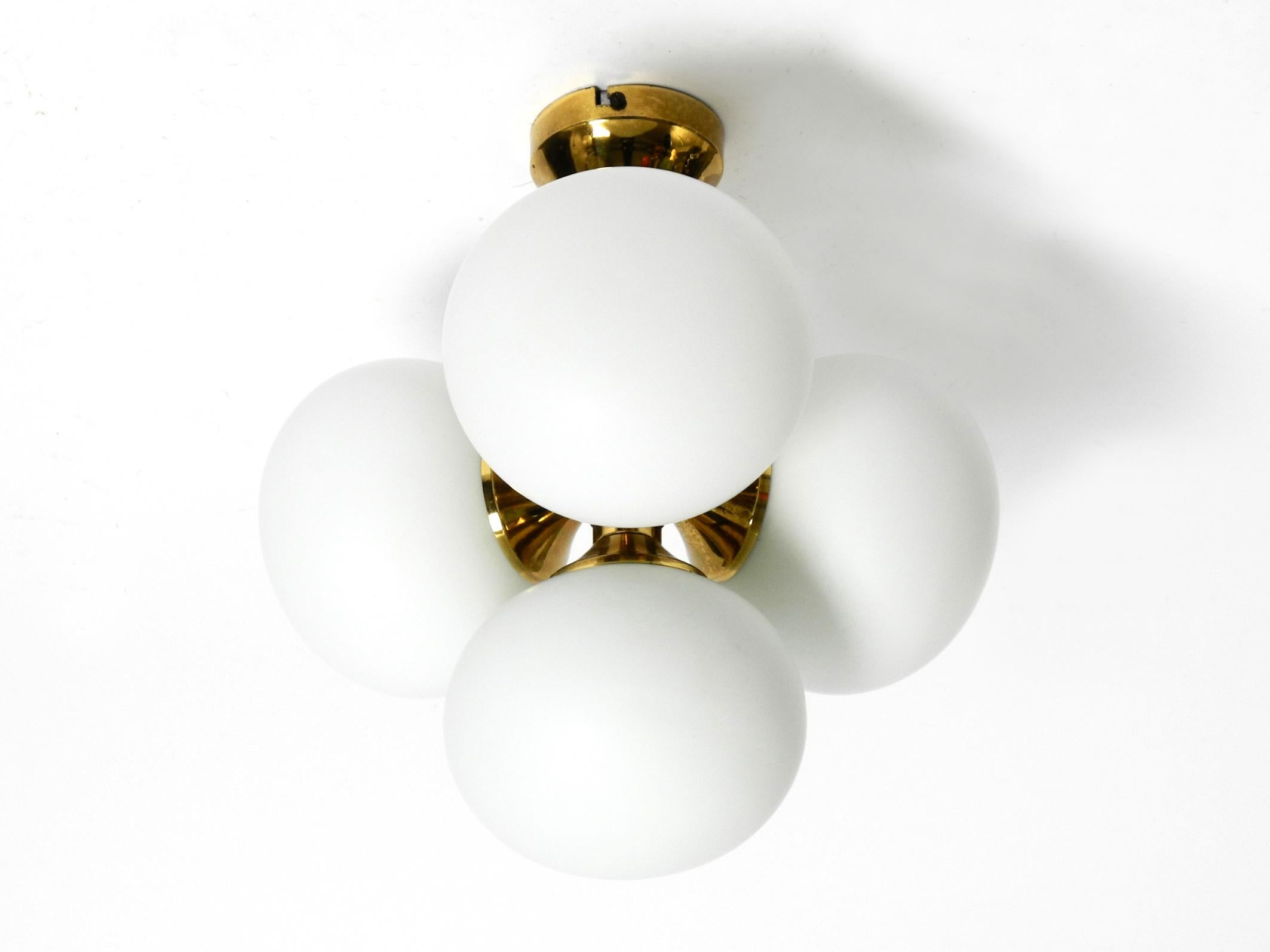 Beautiful rare 1960s brass ceiling lamp with 4 white glass spheres. Frame is completely made of brass. Manufactured by “Kaiser Leuchten”. Made in Germany.
Super Sixties Space Age design for great, glare-free light.
Four E14 sockets for a maximum of