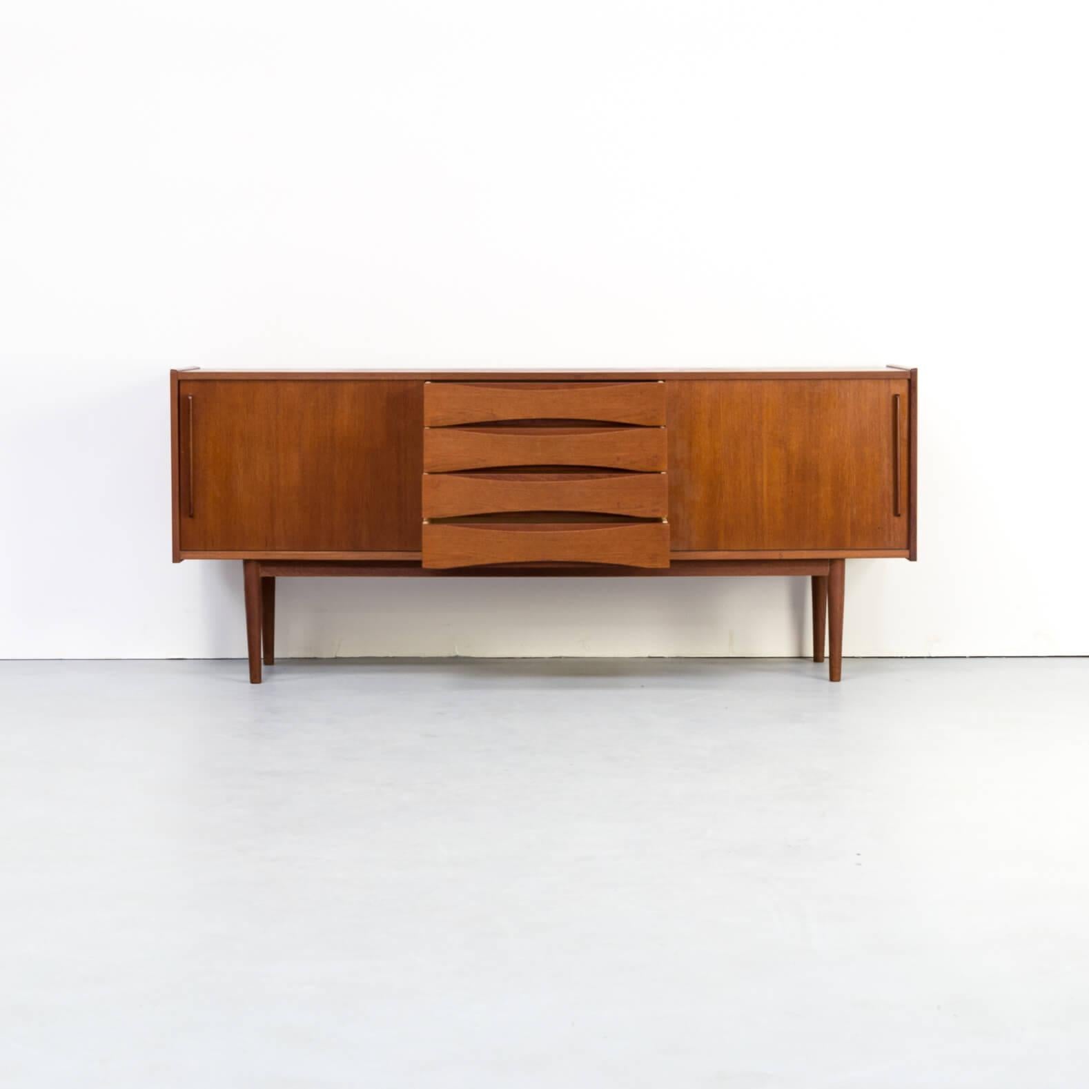 This midcentury teak veneer sideboard has a simple though strong design. Two sliding doors and 4 drawers. It is in very good condition consistent with age and use.