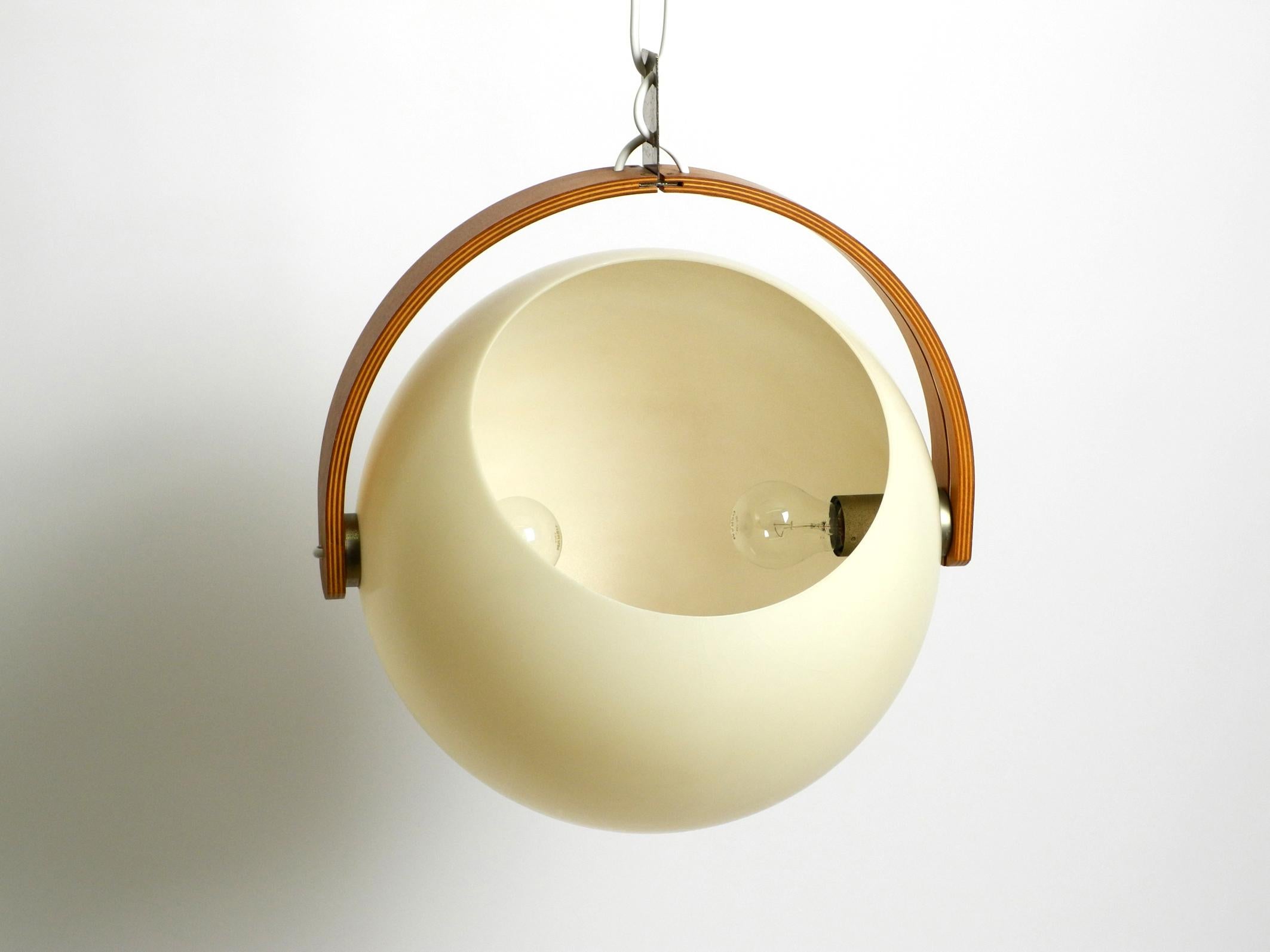 Beautiful and very well preserved vintage ceiling lamp by Temde, an original from the 1960s.
Typical high-quality Space Age design from that time. The lamp consists of a large beige plastic ball with one opening and one teak plywood frame made of a