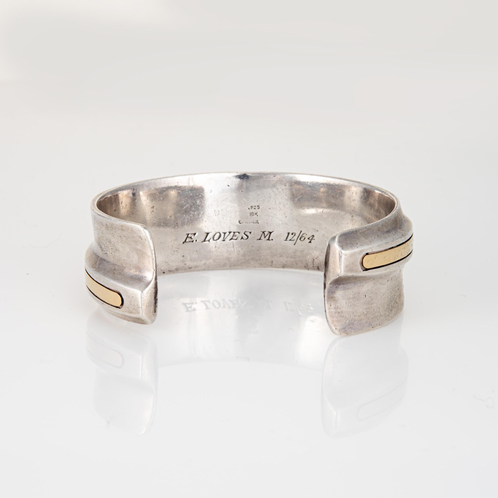 
Stylish vintage Cartier cuff bracelet crafted in sterling silver and 18 karat yellow gold (circa 1964).  

The sculptural cuff is a Cartier classic, with a raised gold applied center and sterling silver surrounds. The inner bracelet is engraved 
