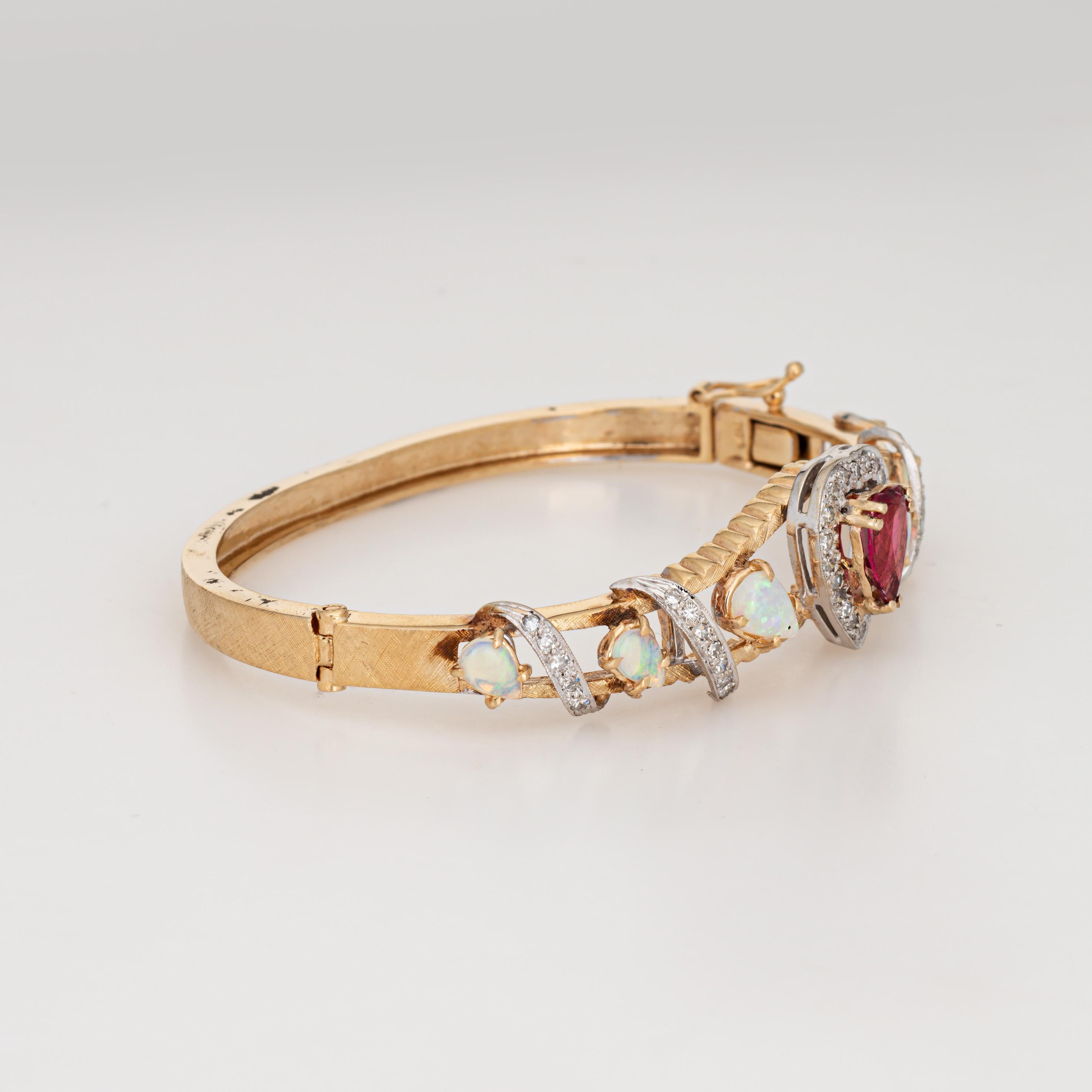 Stylish and finely de1ailed vintage opal & pink tourmaline bangle bracelet crafted in 14 karat yellow gold (circa 1960s). 

Heart cut pink tourmaline measures 9mm x 7mm. Opal graduate in size from 5mm x 3.5mm to 7mm x 5mm. The opals are in good