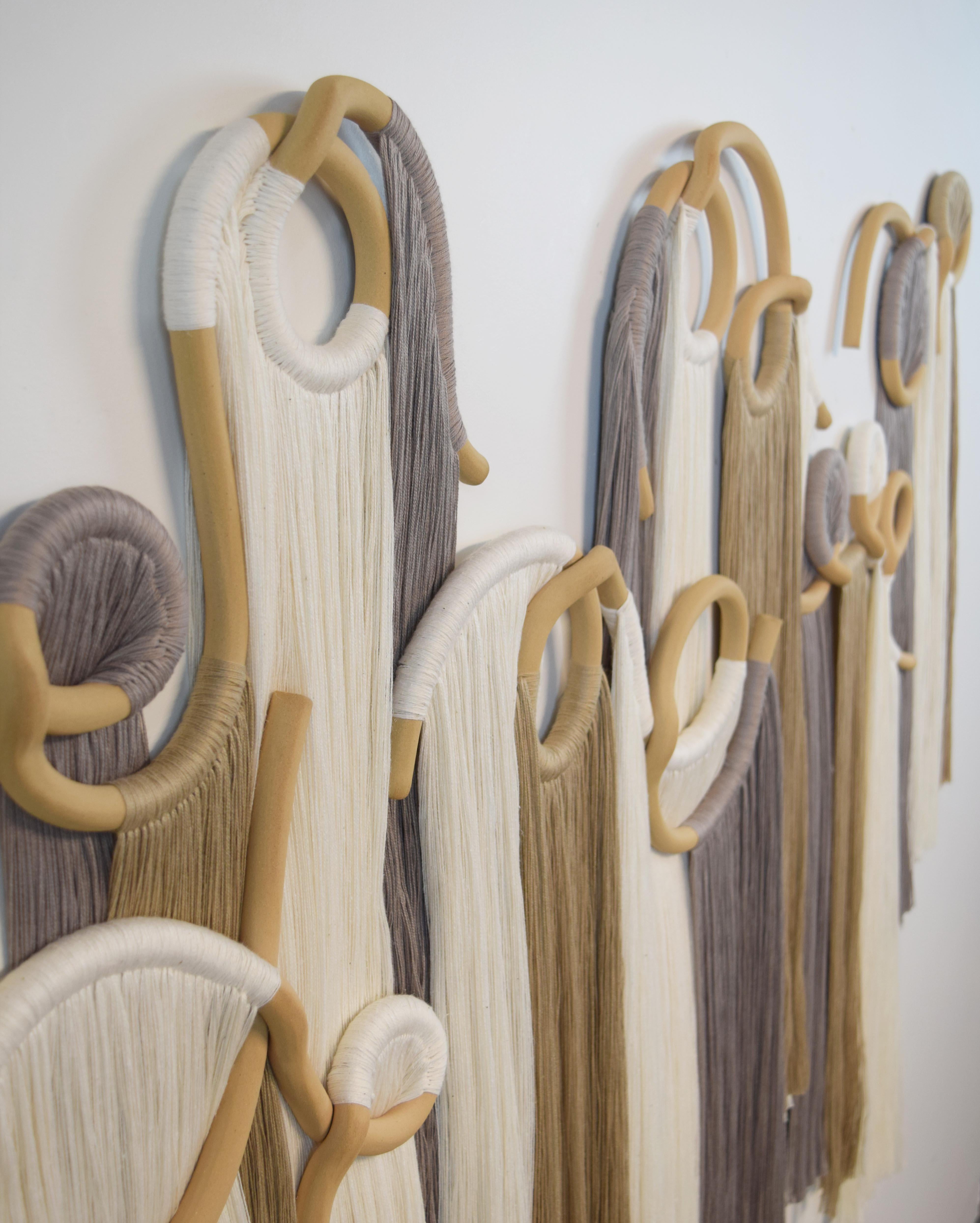 Wall Sculpture #765 by Karen Gayle Tinney

Six panel wall sculpture. Hand formed ceramic pieces in unglazed beige stoneware with white, tan, and gray cotton fringe. Hanging wires are included on each panel. Ships with a small comb for fringe and