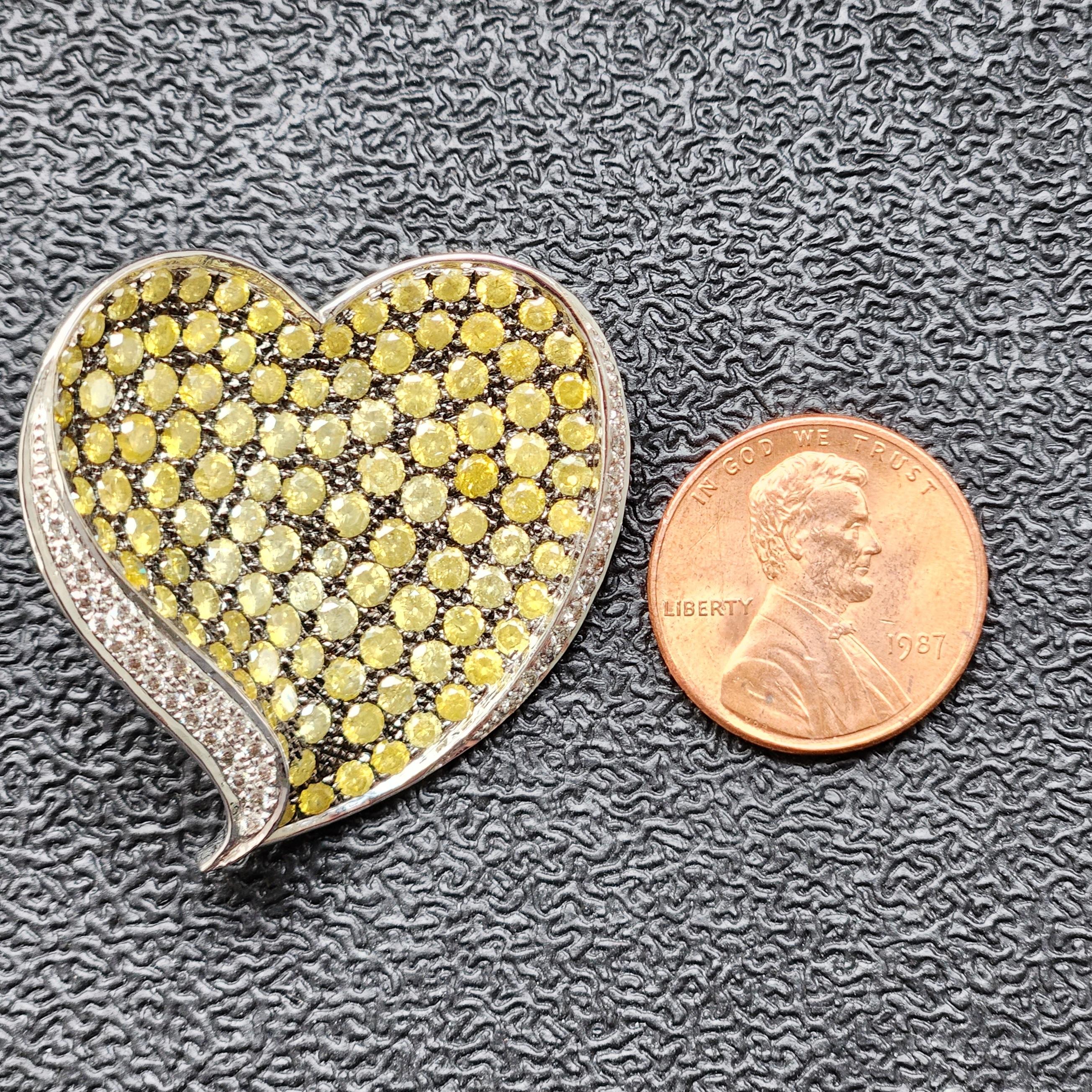 Introducing the Greenish Yellow Heart-shaped Brooch Pendant, a stunning piece of jewelry that's magnificiant. Featuring a glittering natural greenish-yellow melee diamond set in 18k white gold and bordered with white melee diamonds, this brooch is