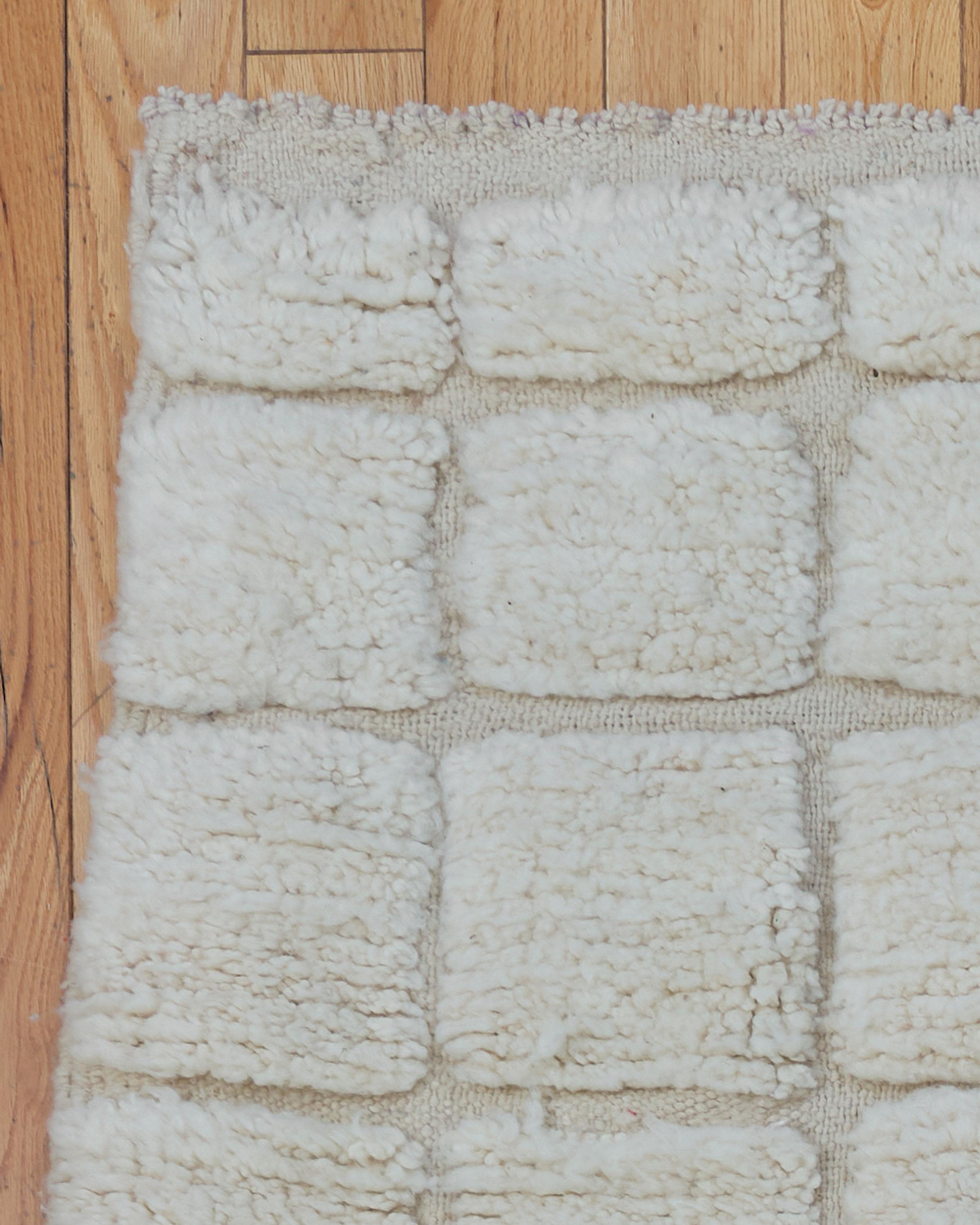 The Columba rug is a stunning Beni Ouarain piece, handwoven by Berber artisans in the Atlas Mountains of Morocco. Featuring a rich cream background, this rug showcases intricate, minimalist geometric designs that are characteristic of traditional