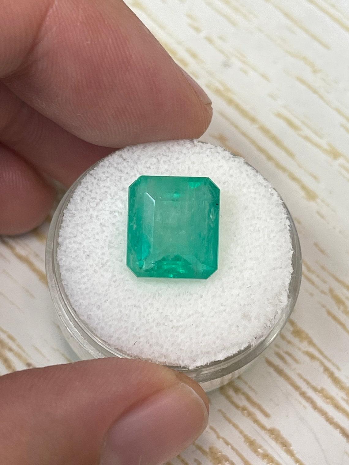 Stone: Emerald
Weight: 6.13-carats
Shape: Emerald Cut
Clarity: Semi-Transparent
Luster: Good
Color: Medium Bluish Green
Measurements: 11.47mm x 10.34mm x 6.90mm
Geographic Origin: Colombia
Treatment: Natural, Oiling

Comments: Due to their growth