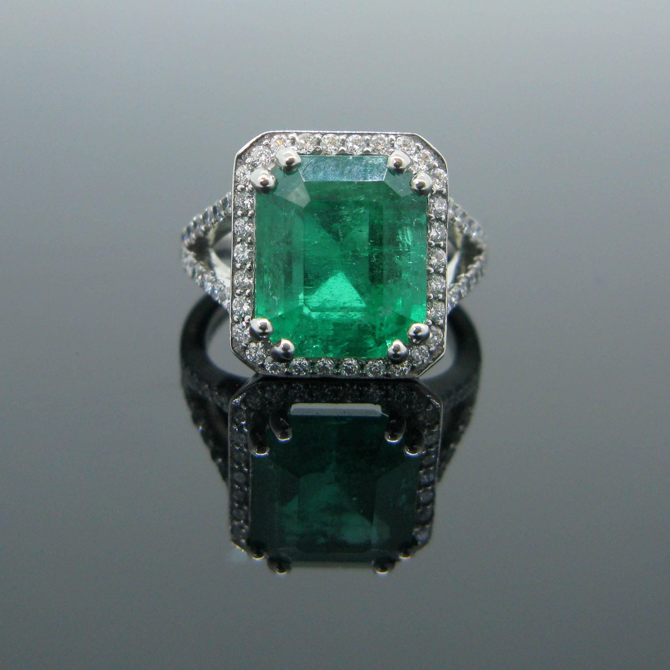 This stunning new ring is made in platinum and features a magnificent 6.14ct Colombian emerald with a vibrant green color. The stone is surrounded with 30 small diamonds and 28 diamonds on each side of the ring. Emerald is also known as the stone of