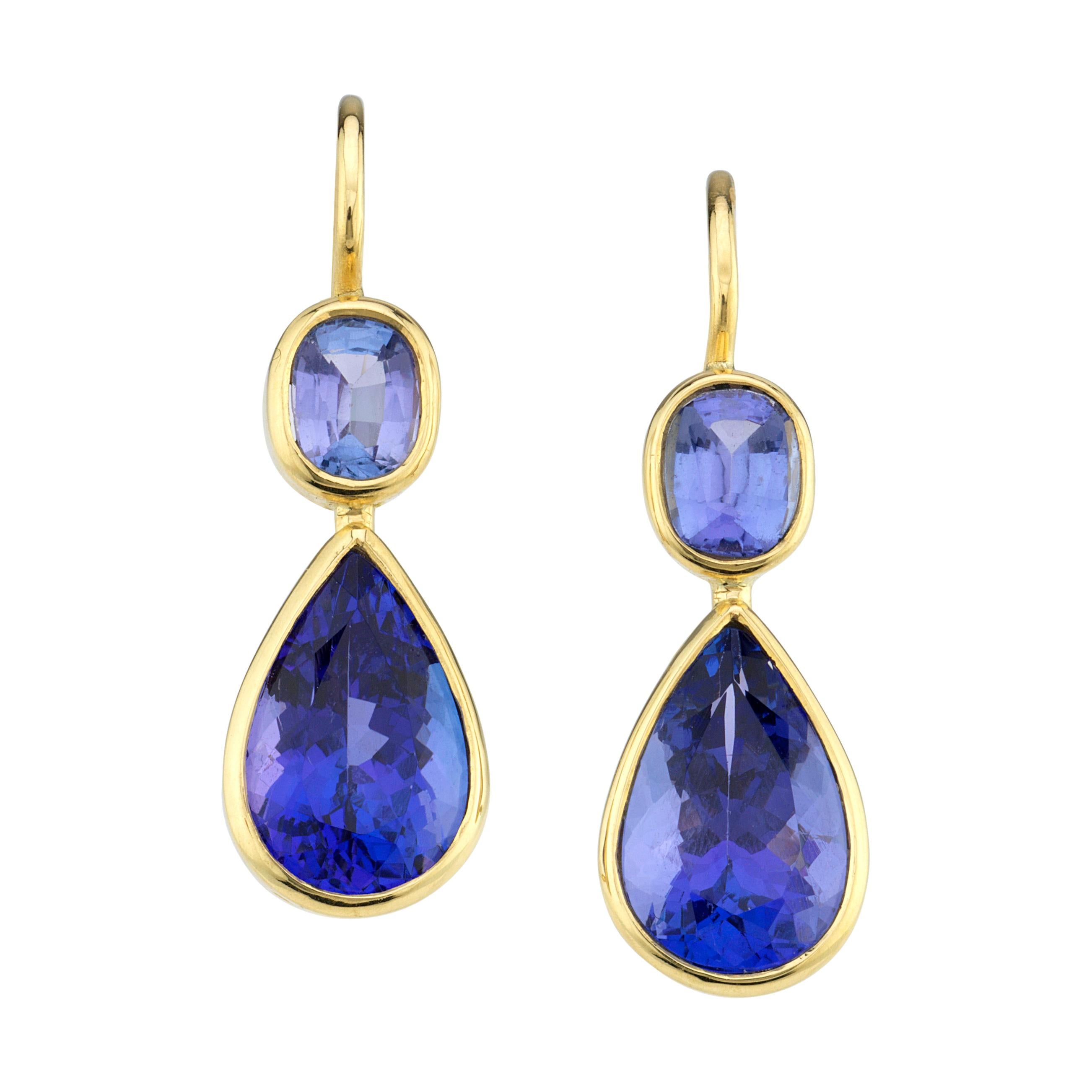 These tone-on-tone tanzanite earrings are suitable for day to evening wear.  Each earring is comprised of a light, violet colored, cushion shape tanzanite and a rich, medium-dark violet, pear shaped tanzanite. The tanzanites are bezel set in 18