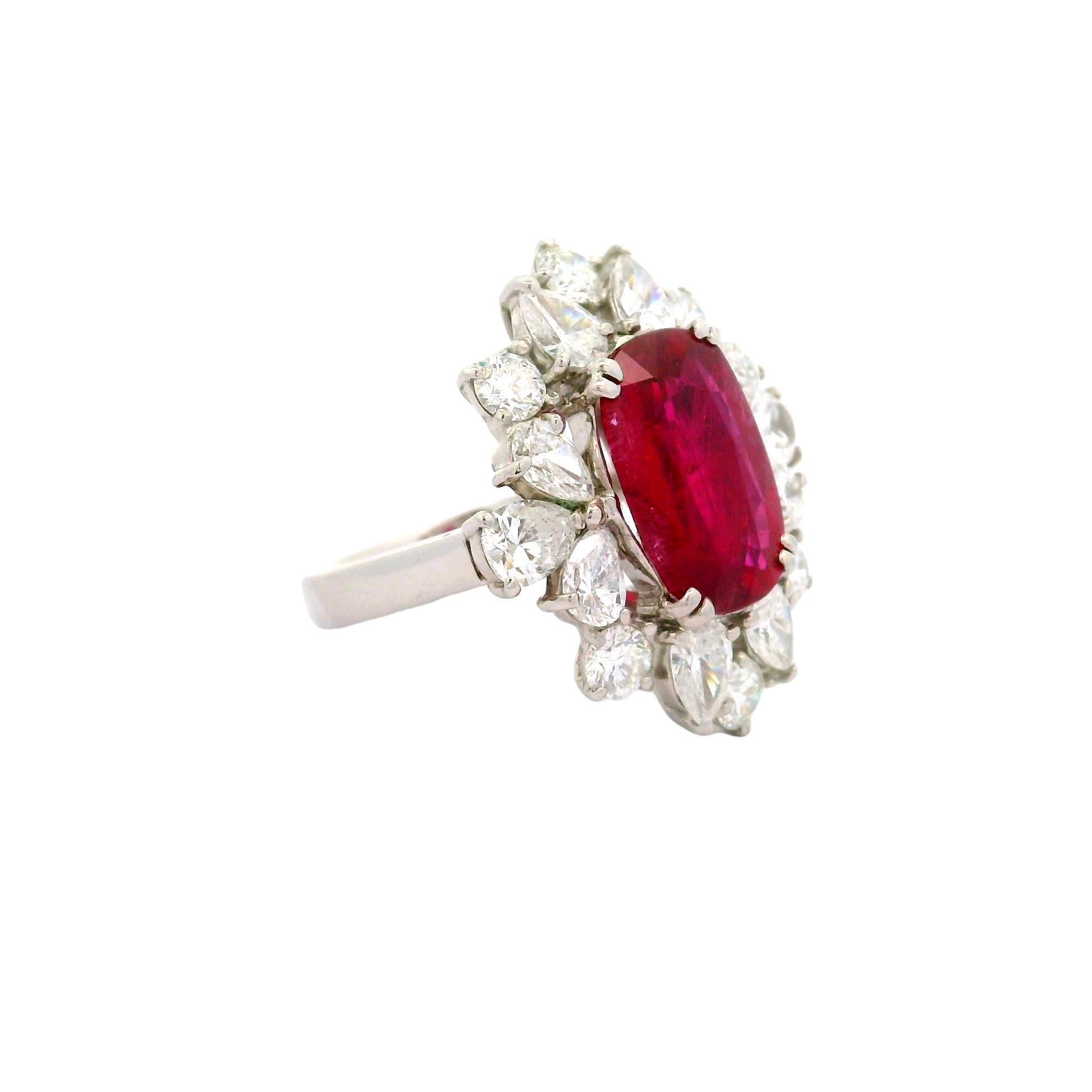 A contemporary ring crafted in platinum, featuring a striking 6.16 carat oval-cut ruby with a vivid red color. The ruby's intense hue commands attention with its vibrant presence. It is accented by 3.30 carats of mixed-cut white diamonds, adding