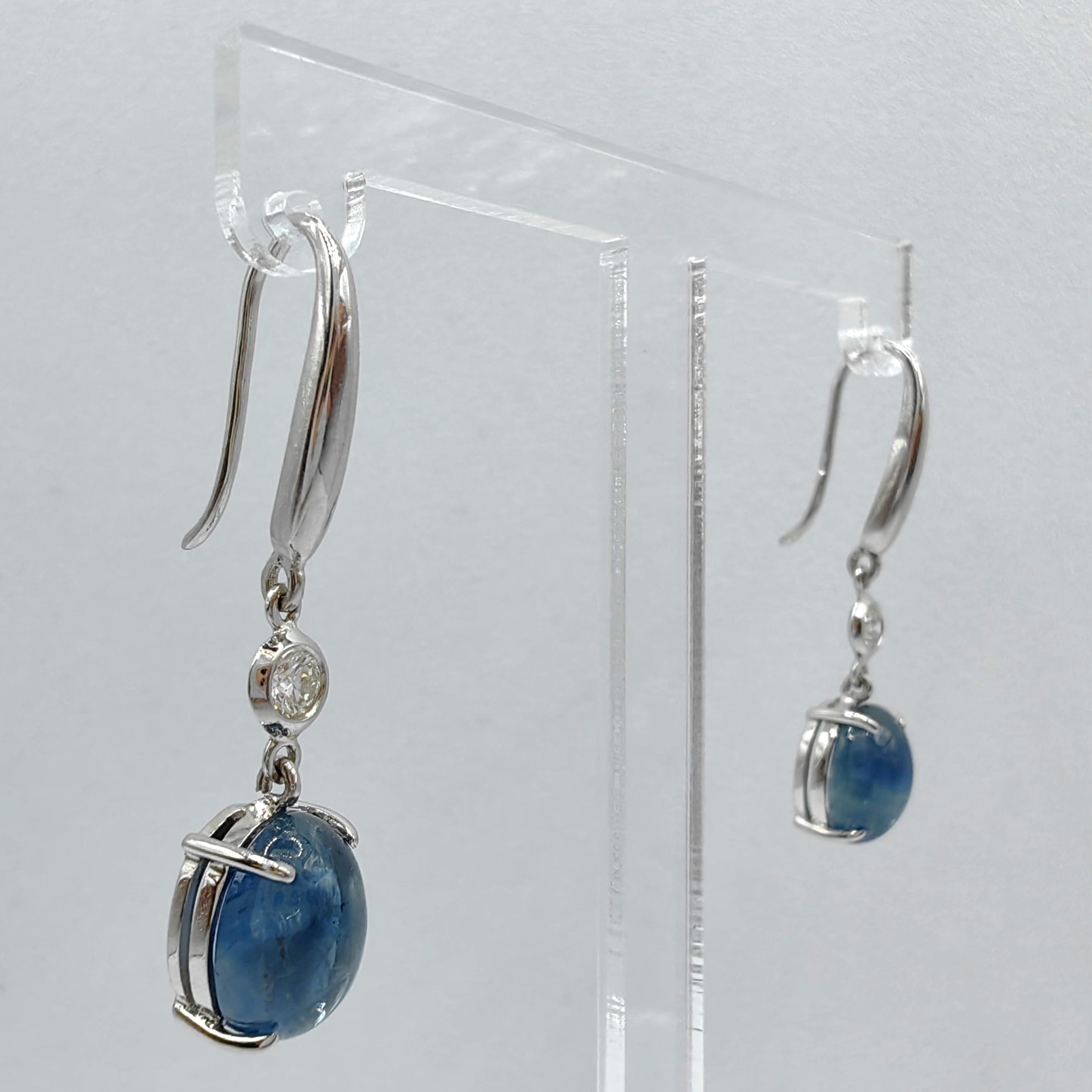 Introducing our exquisite 6.18ct Cabochon Blue Sapphire Diamond Dangling Earrings, where the captivating beauty of blue sapphires and brilliant diamonds takes center stage. 

At the heart of these earrings are two mesmerizing cabochon blue