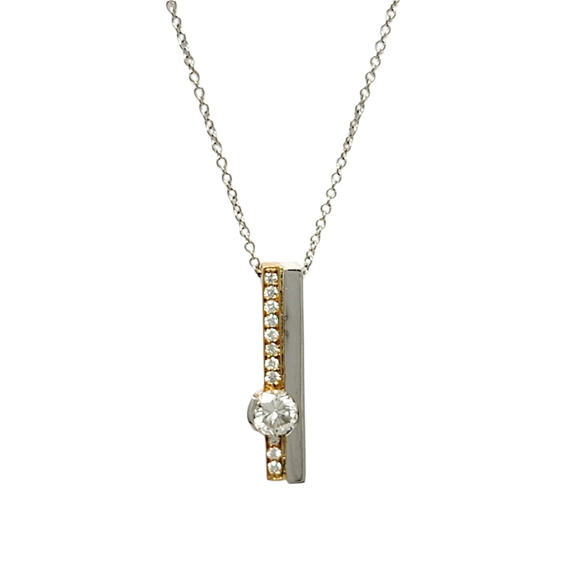 Gorgeous, contemporary necklace with sleek double bar shape. The pendant is 18 karat yellow gold and white palladium. The chain is 14 karat white gold The pendant main diamond is semi bezel set and is round brilliant cut, approximately .51 carats,