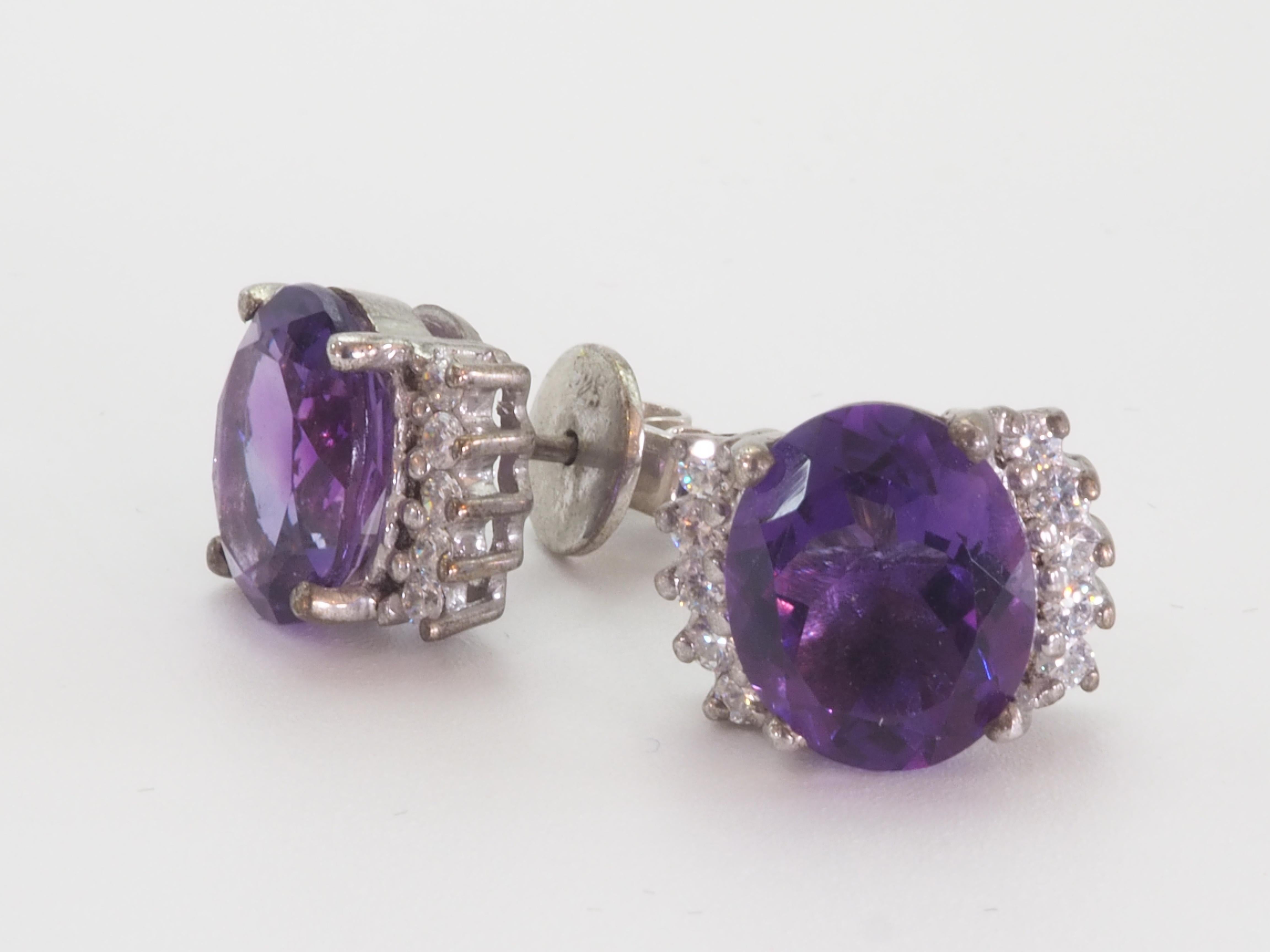 This earring is a beautiful statement stud piece featuring good color and clarity oval amethysts. The amethysts are of decent size- visible from afar. The white gemstones accenting are white quartz. This is the earring suited for special events.