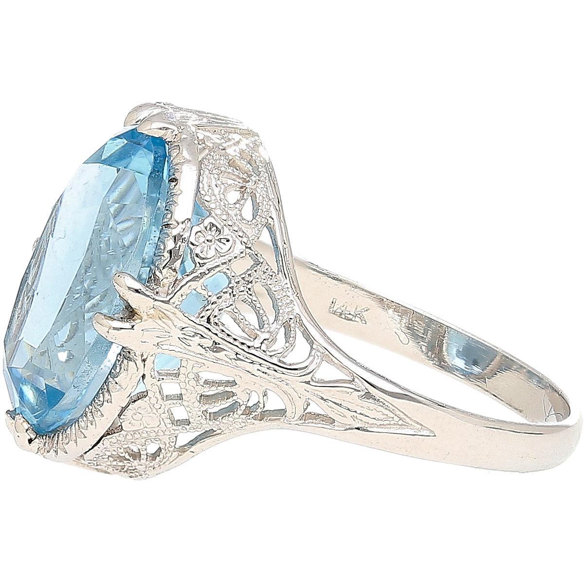 Edwardian-inspired filigree ring showcasing a stunning 6.22 carat oval cut aquamarine set in intricately engraved 14K white gold. Its openwork floral detailing and elevated crown-like bezel create a bold yet elegant statement. Ring size 7,
