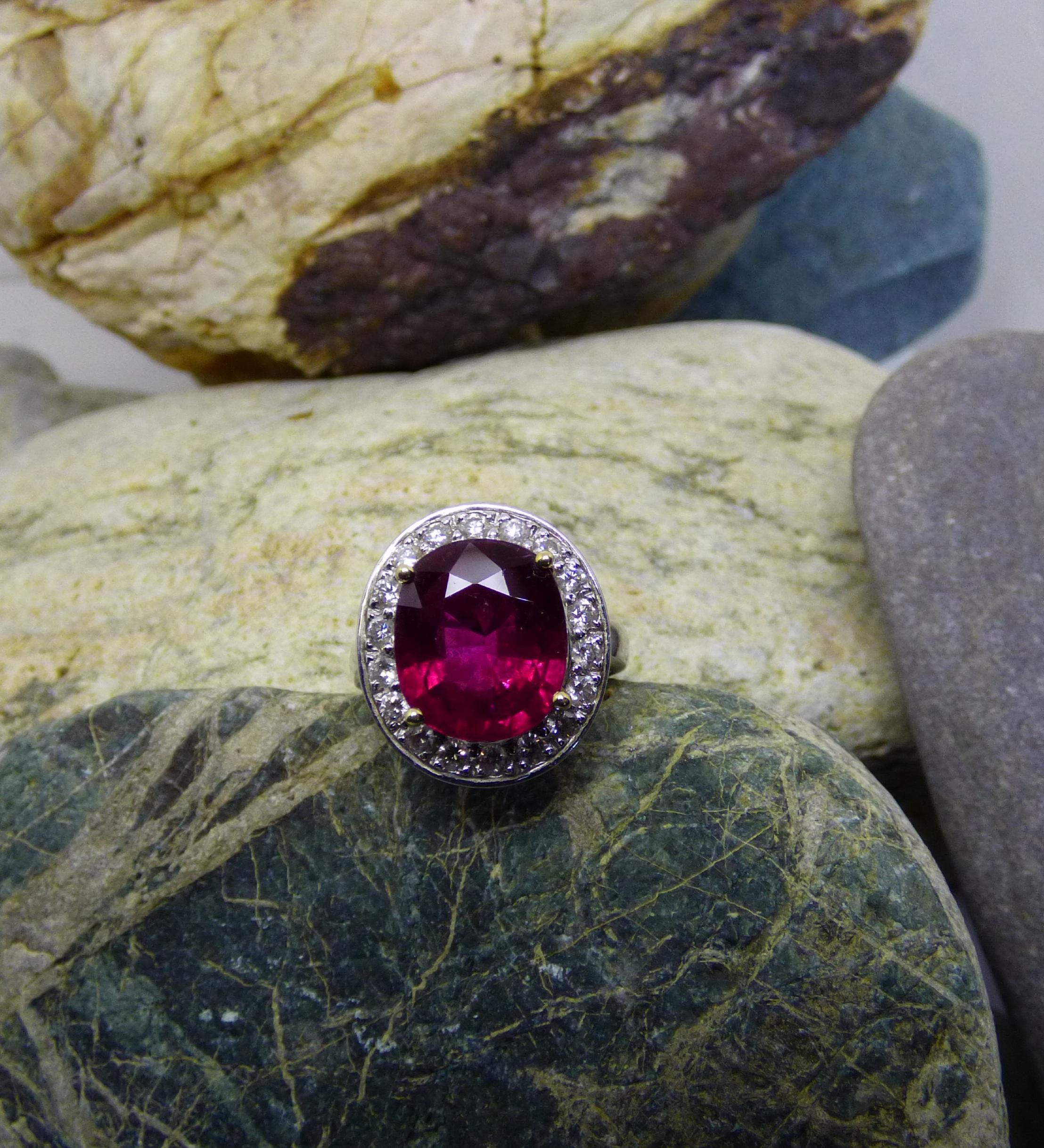 A bright and colourful Rubellite Tourmaline attracts the eye to this ring.  The Rubellite is 15X12mm and weighs 6.22ct. It is surrounded by 17 Diamonds with a total Diamond weight of 1.71ct. The total face of the ring is 22X19mm.
The ring is