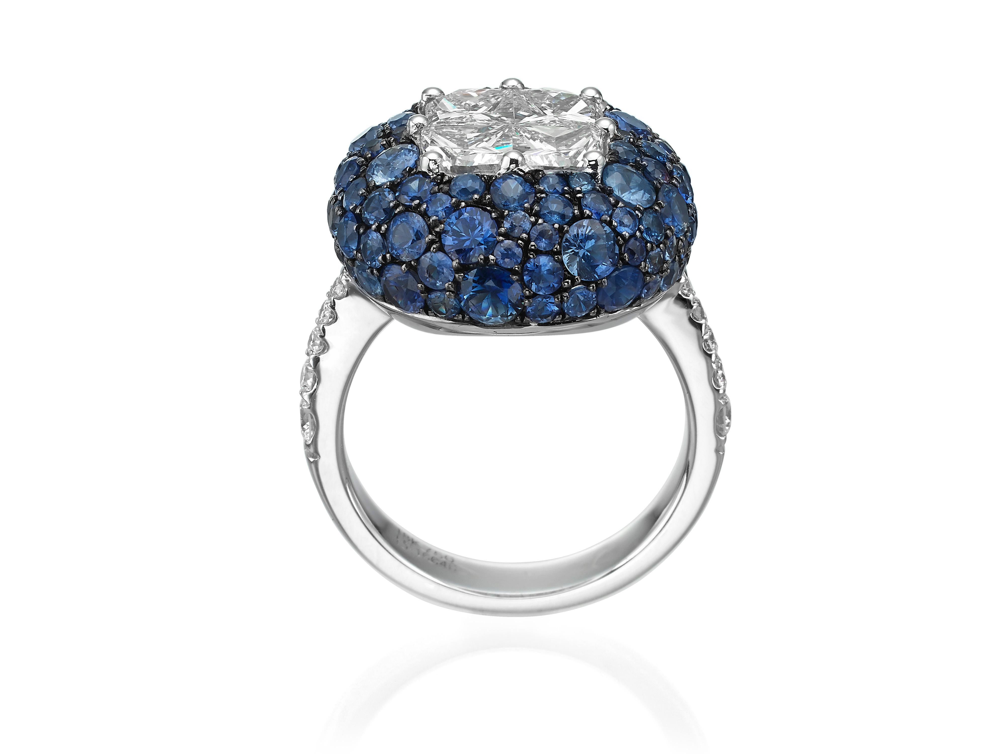 Handcrafted in 18K white gold, this stunning ring is centered with four white diamonds (totaling 1.9 carats) to create an illusion of one large single white diamond.  Surrounded by a cluster of 98 round blue sapphires (totaling 4.05 carats) and 0.29