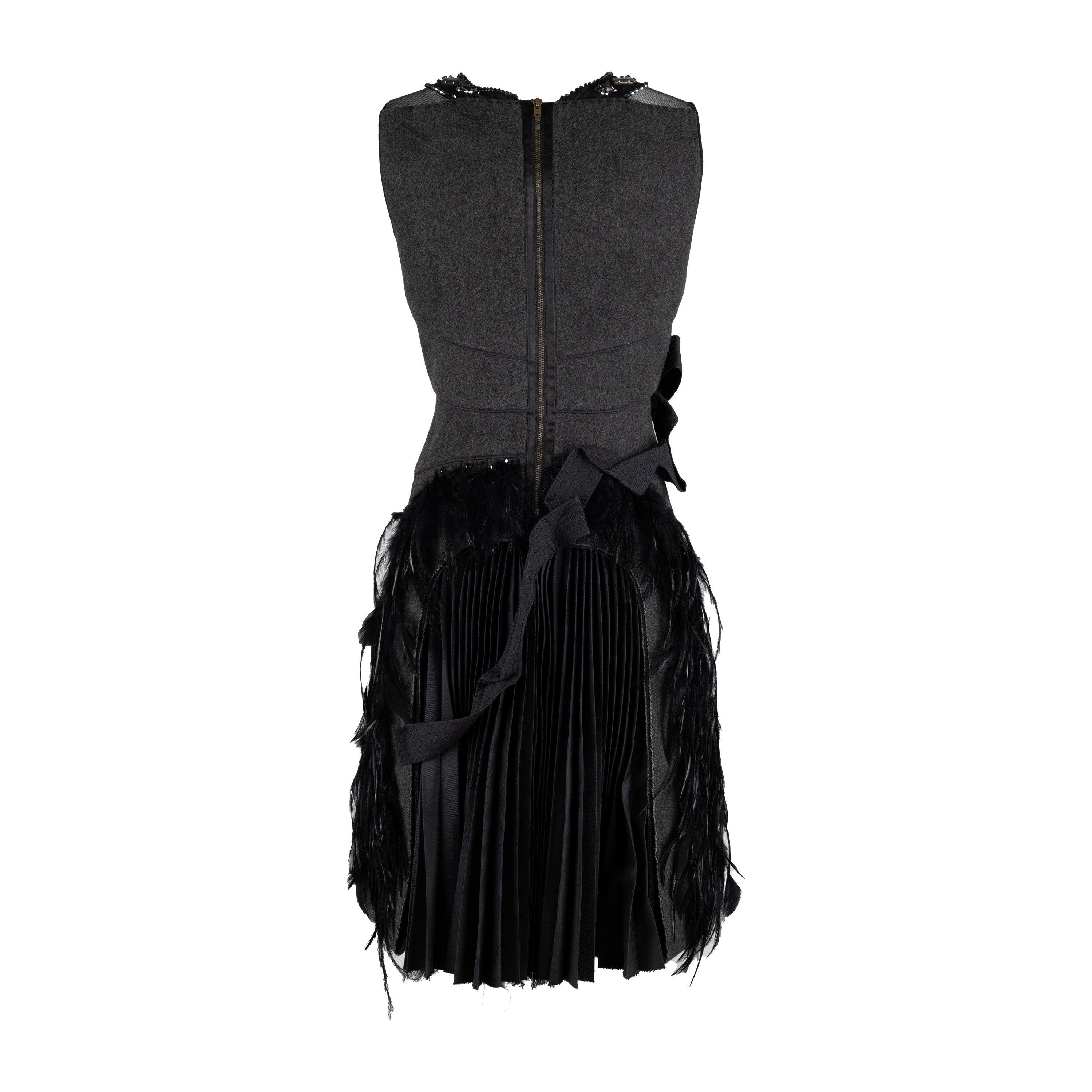 This 6267 Compact Wool Dress in a grey hue is crafted from a wool blend and adorned with iridescent beads, rhinestones, and exotic feather embellishment. The round neck is highlighted with beaded details and the fitted silhouette flows to a hem with