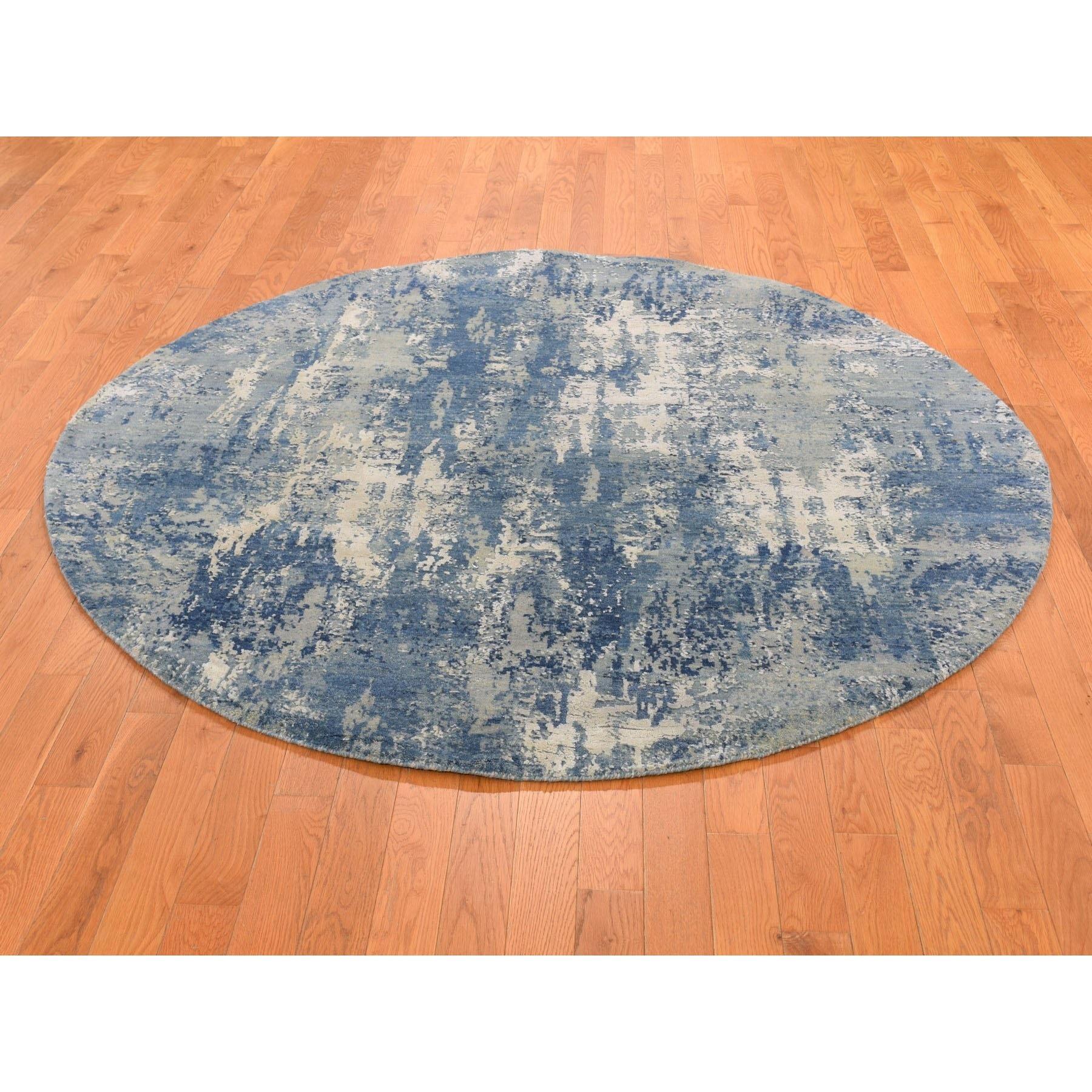 Il s'agit d'un véritable tapis d'Orient, unique en son genre, au design abstrait et rond, en laine et soie bleue, noué à la main et tissé de façon plus dense. Il a été tissé pendant des mois et des mois selon les techniques séculaires de l'artisanat