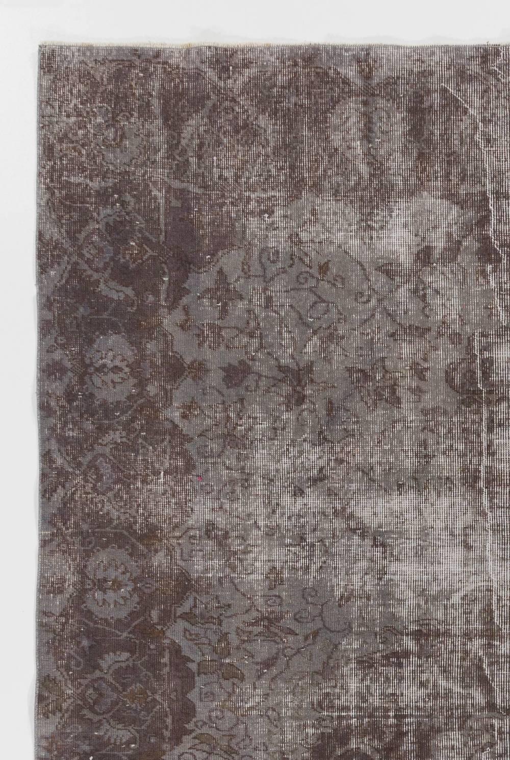 A vintage handmade Turkish rug over-dyed in taupe and gray featuring a medallion design against a field decorated with scrolling leafy vines. The rug is finely hand-knotted and has distressed low wool pile on cotton foundation. It is deep-washed, in