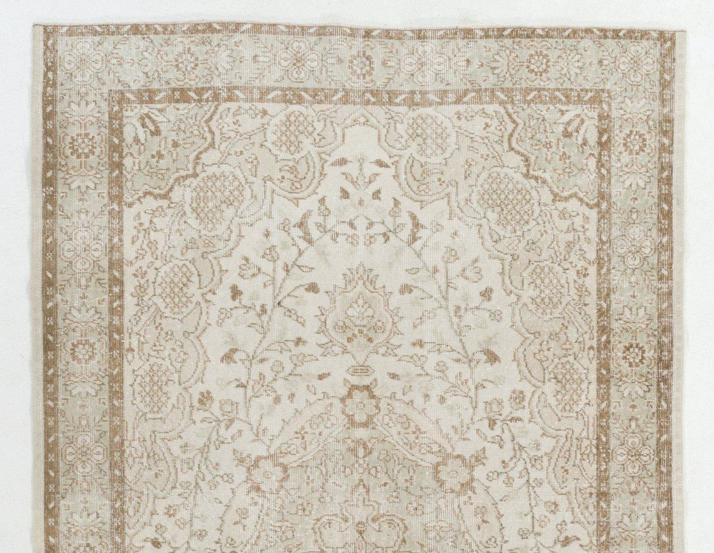 This handmade vintage Turkish Oushak area rug was hand-knotted in the 1960s with distressed low wool pile on cotton foundation. The rug has a central medallion on a field decorated with lush scrolling floral vines and pomegranates in a muted color