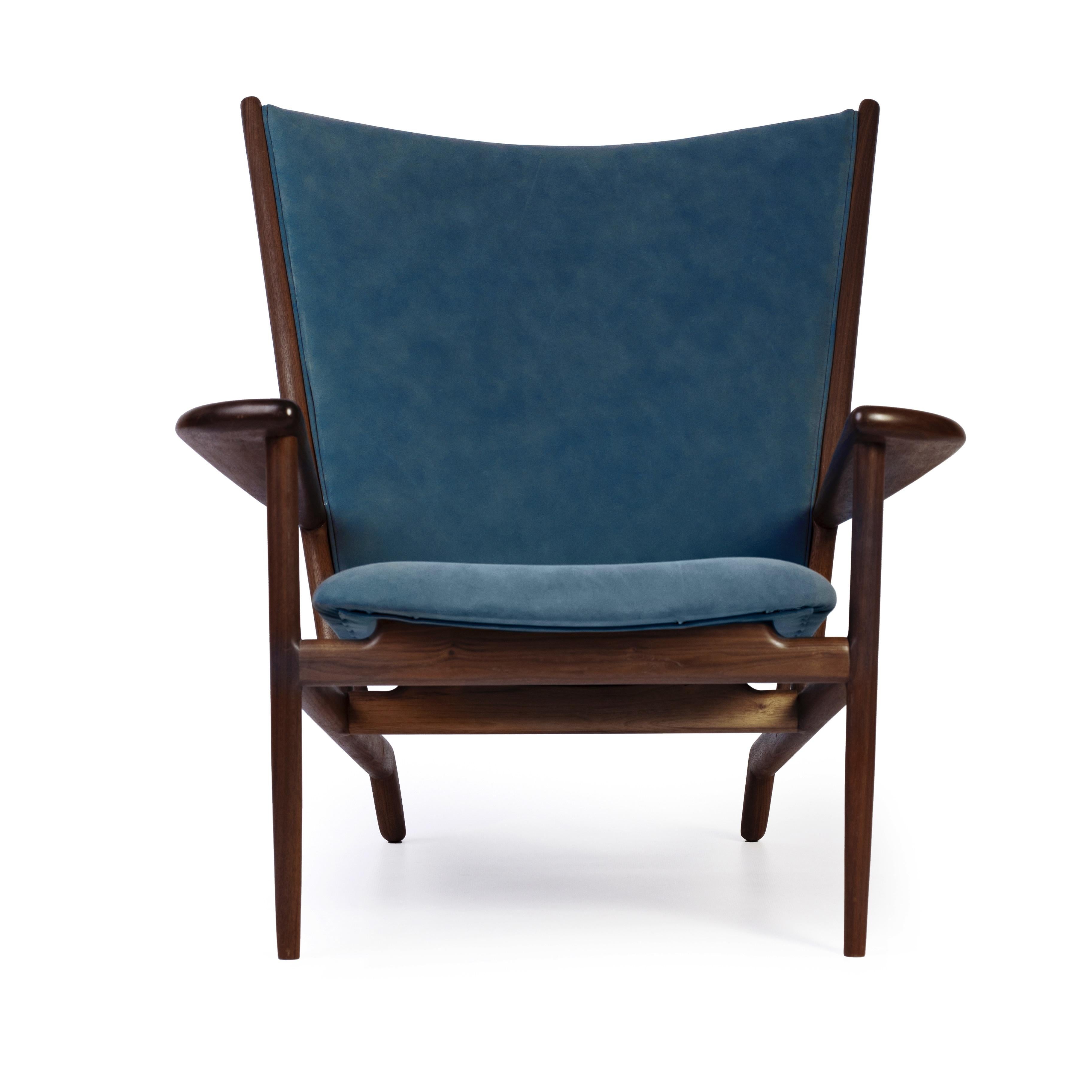 Introducing the 63 chair, a stunning mid-century modern statement piece handcrafted with exceptional woodworking techniques and premium leather upholstery. This impressive chair boasts a robust walnut frame, carefully selected for its rich grain and