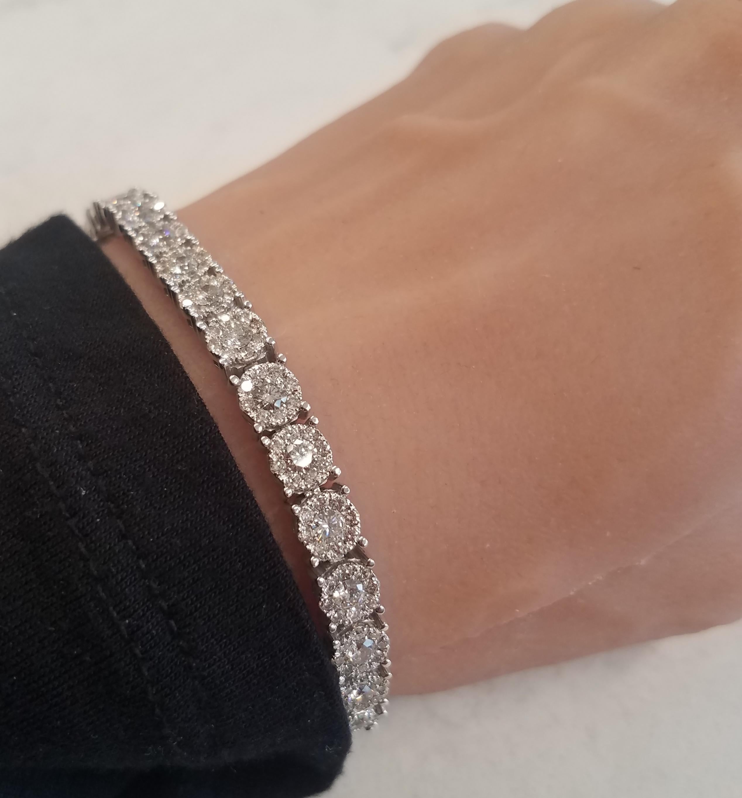 This brightly polished 14k white gold eternity bracelet showcases 261 sparkling round brilliant cut diamonds prong set into circular disc halo links in a dazzling display, totaling 6.30 carats. Perfect for anniversaries, this gorgeous tennis