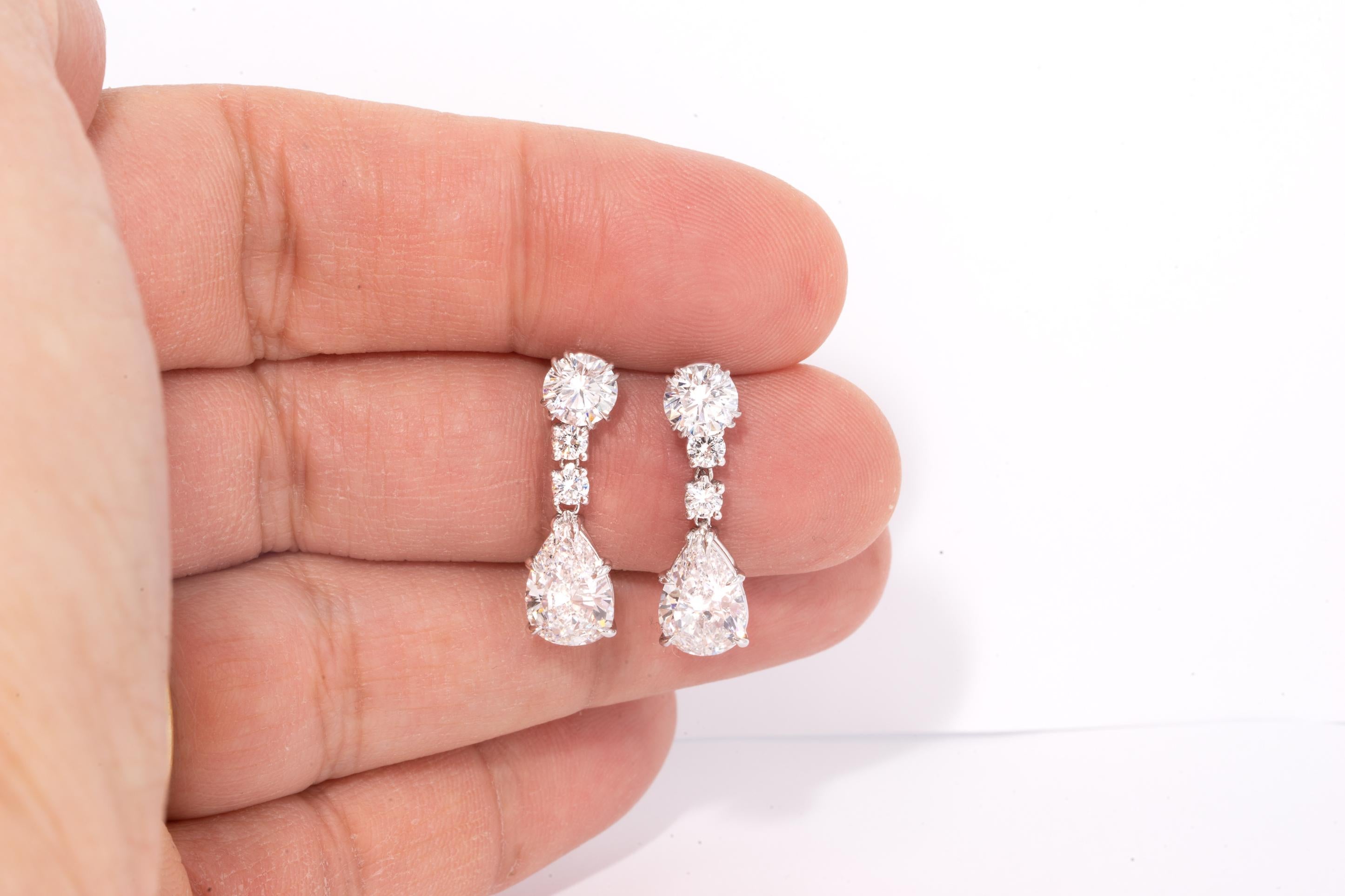 Pair of dangling earrings with 2 perfectly matched pear shape diamond centers
Pear Shape centers weigh 4.02 carats total 
Larger Round Centers weigh 1.81 carats total, 
Smaller rounds weigh .48 carats total
Total diamond carat weight , is 6.31