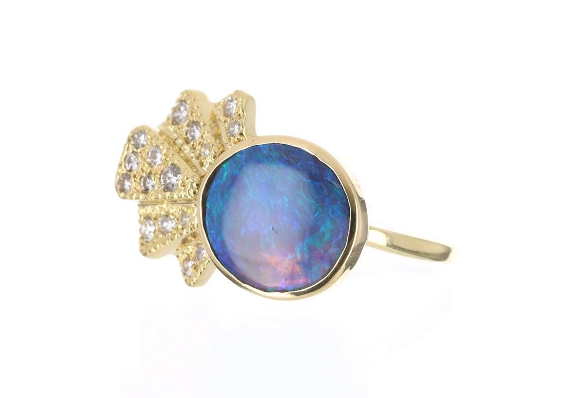 Displayed is a ravishing, Australian black opal and diamond right hand ring. This piece is as chic as it is beautiful. The focal point of the ring is a solid black opal displaying beautiful play-of-color. The cabochon shaped opal has fire,