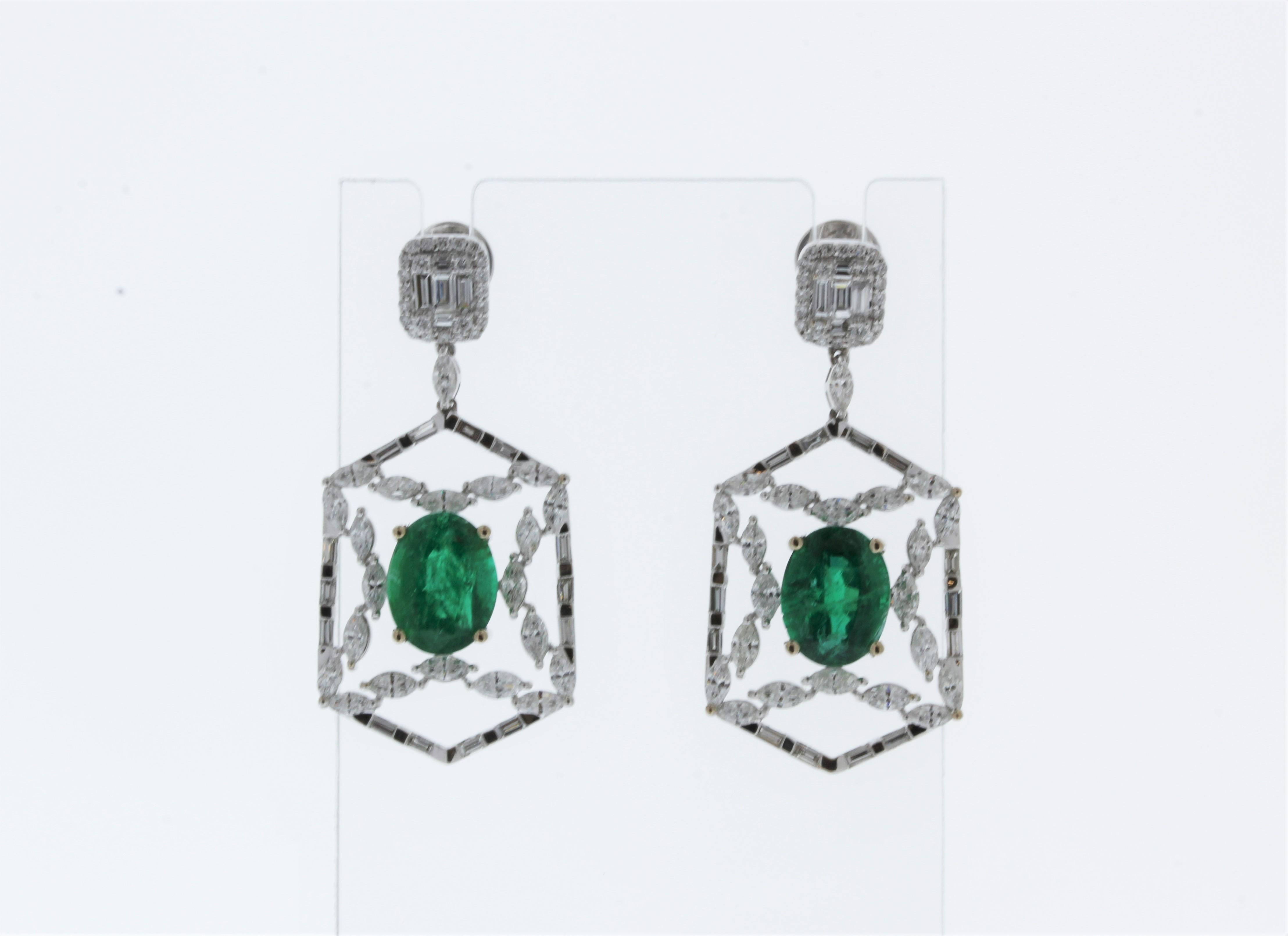 These are vintage-inspired emerald and diamond earrings. Two stunning oval shaped green emeralds, weighing 6.33 carats total, delicately centered. The emeralds are sourced in Brazil. The clarity and transparency are top-end. The mixed cut diamonds