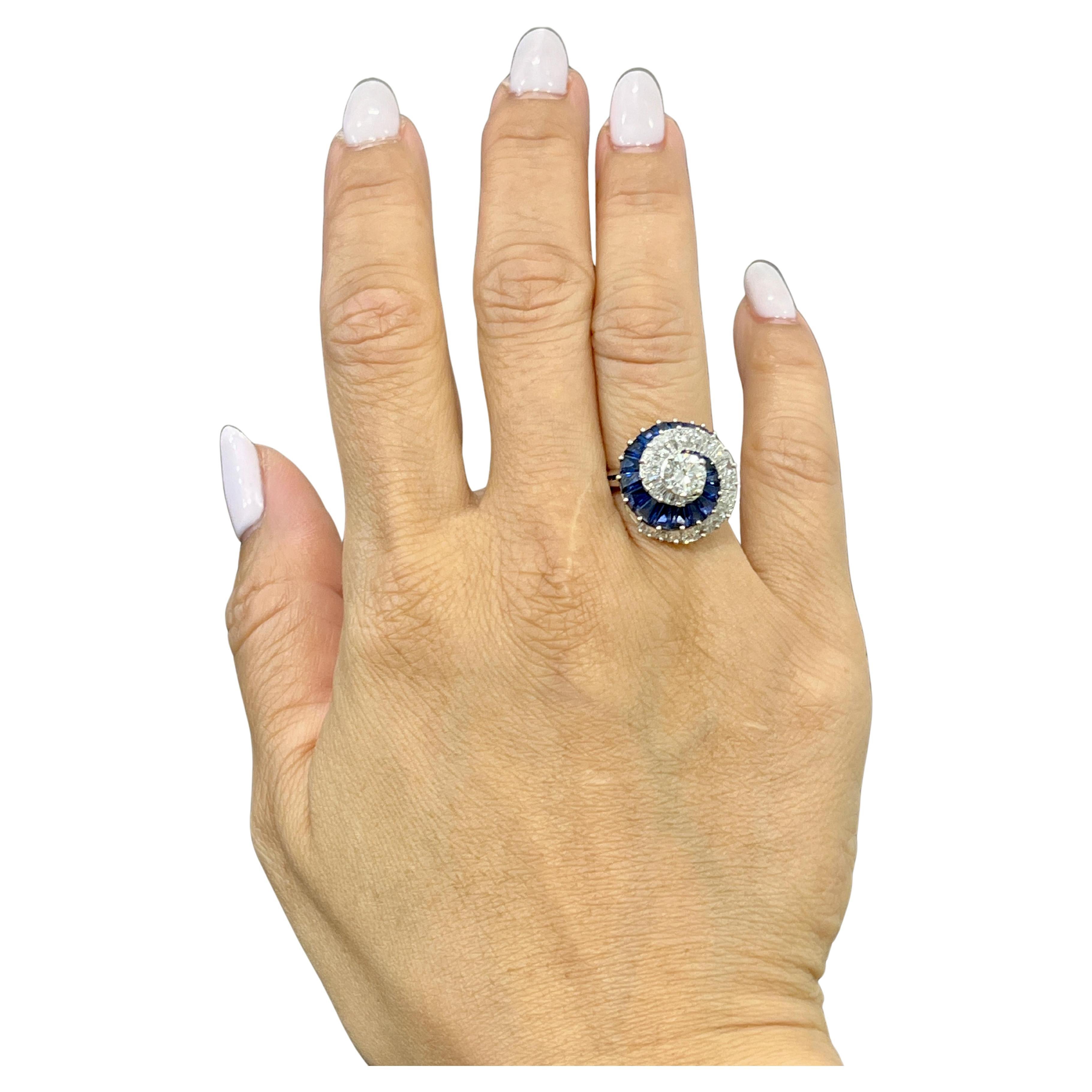 This exquisite cocktail ring showcases a round white diamond weighing 0.87 carats, with a clarity of VS1 and a color grade of D. Surrounding the central stone are 20 tapered blue baguette-cut sapphires weighing 2.58 carats, and an additional 22
