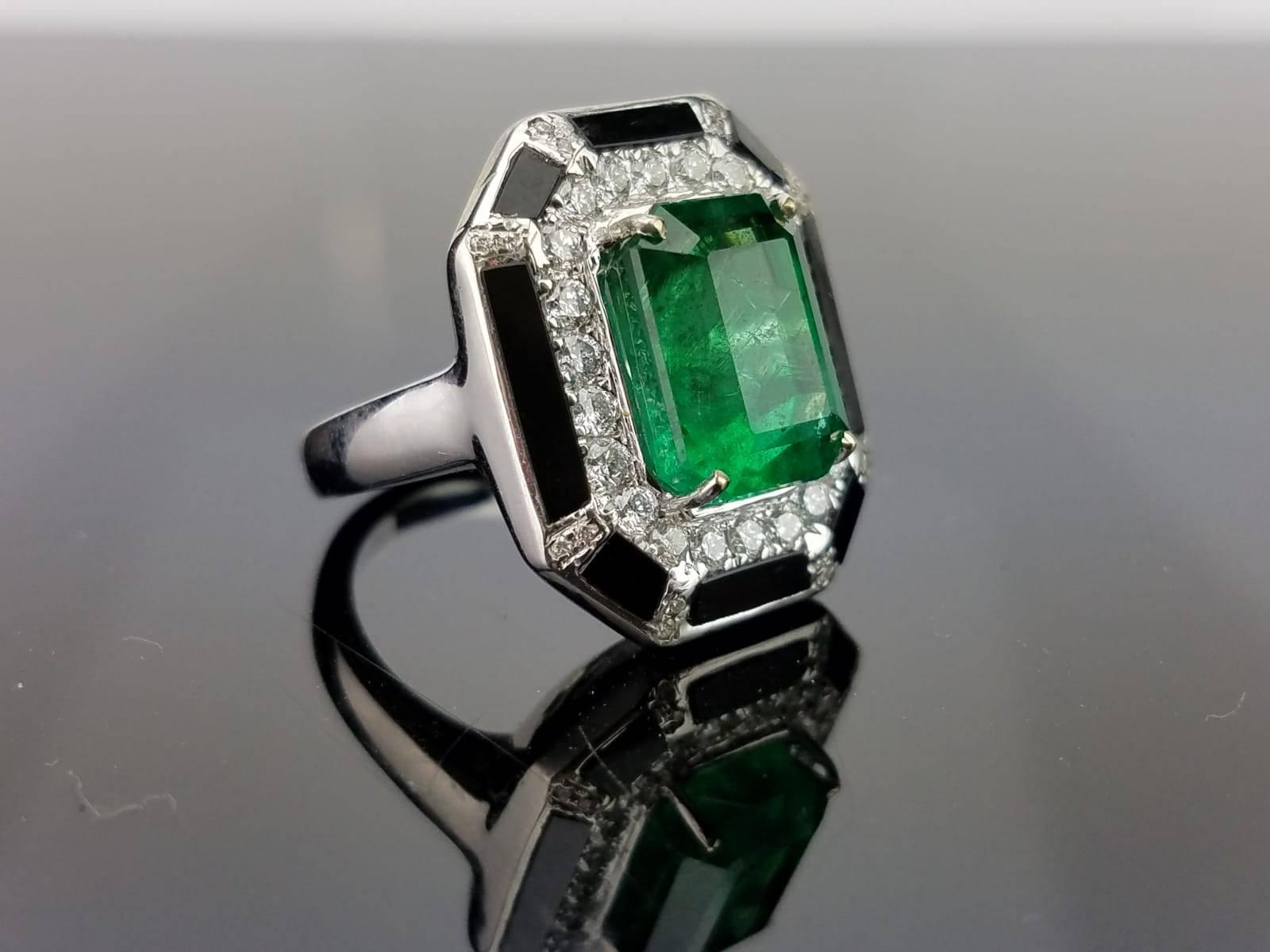 A very art-deco looking cocktail ring, using a Zambian Emerald centre stone and diamonds, as well as black onyx - all set in 18K white gold. 

Stone Details: 
Stone: Emerald
Carat Weight: 6.39 carat

Diamond Details: 
Total Carat Weight: 0.73