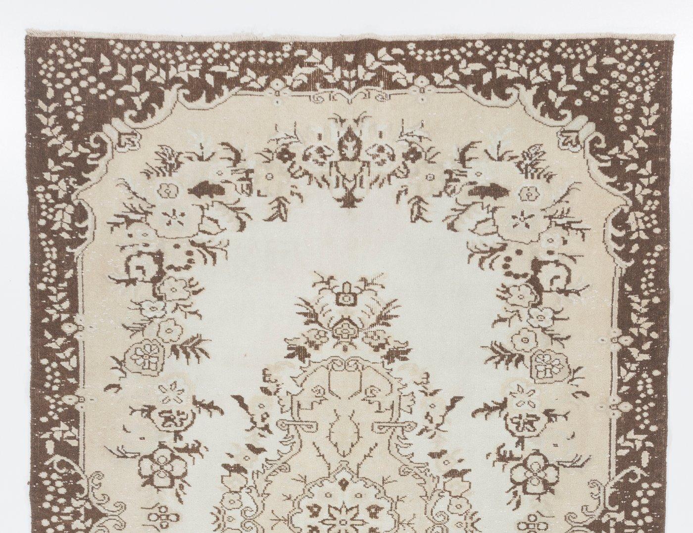 Dies ist ein handgeknüpfter türkischer Teppich im Vintage-Look. Der Teppich zeigt ein florales Medaillonmuster in einem mit floralen Motiven verzierten Feld. Er hat einen niedrigen, strapazierten Wollflor auf Baumwollbasis, ist in sehr gutem