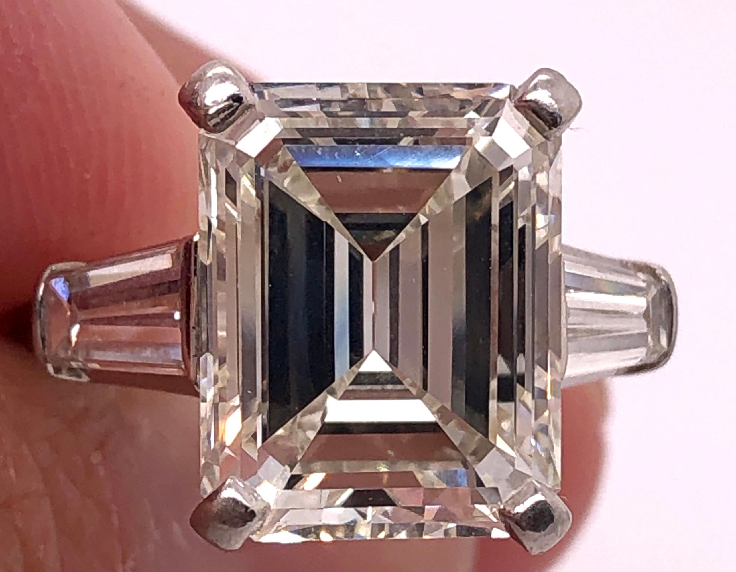 5.68 Ct Smaragdschliff Diamant Verlobungsring VS1 J/K  Farbe mit zwei .75 TDW Steinen auf der Seite. Dieser große und beeindruckende Diamant sitzt in einer Platinfassung mit drei Viertel Karat Diamanten, die den Mittelstein flankieren. Jeder H-I