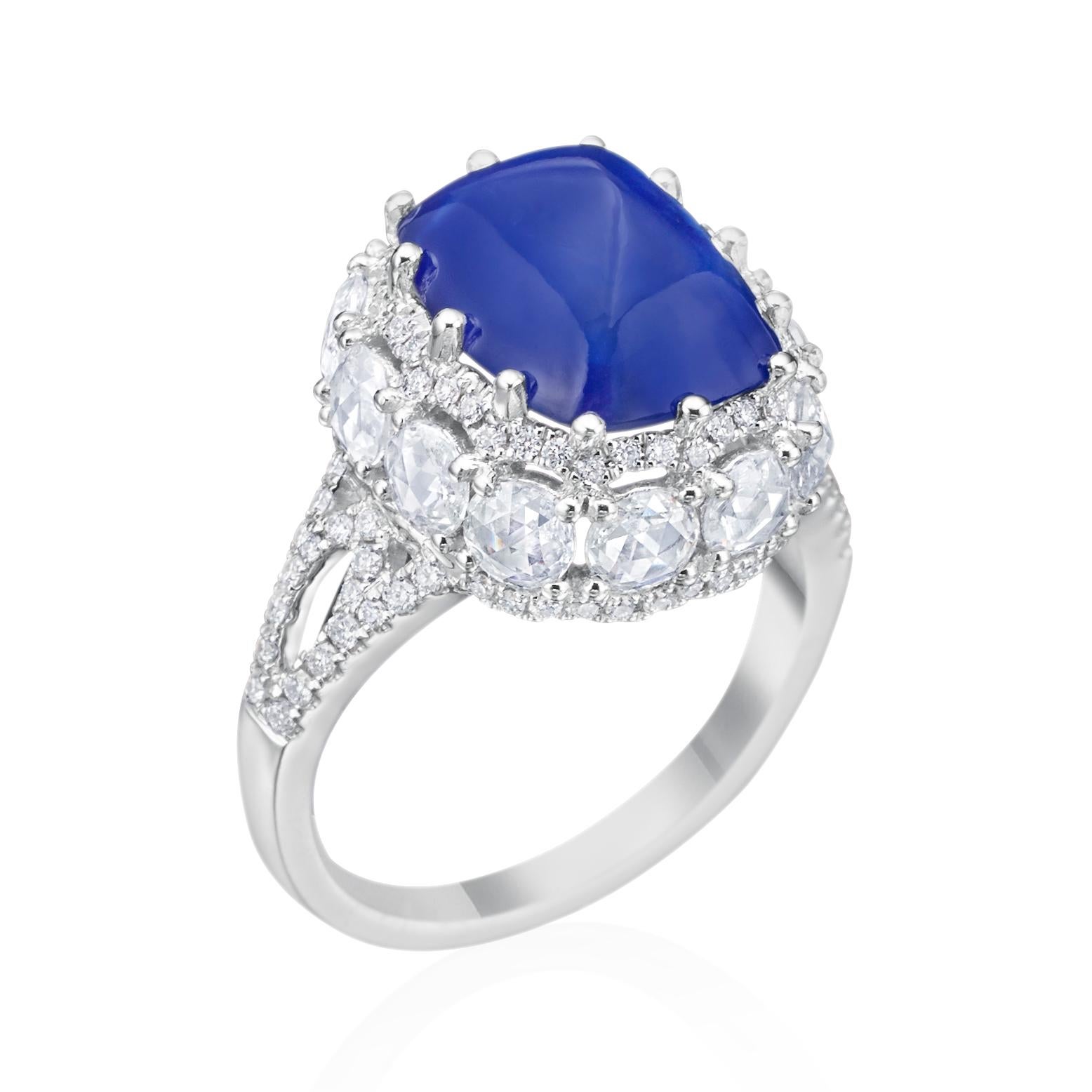 This dazzling 18K white gold diamond ring features a cushion sugar loaf cut blue Sapphire, that weighs 6.44 carats. Accenting this magnificent blue Sapphire, are twelve round rose cut diamonds weighing 1.23 carat with G-H color and VS clarity. The