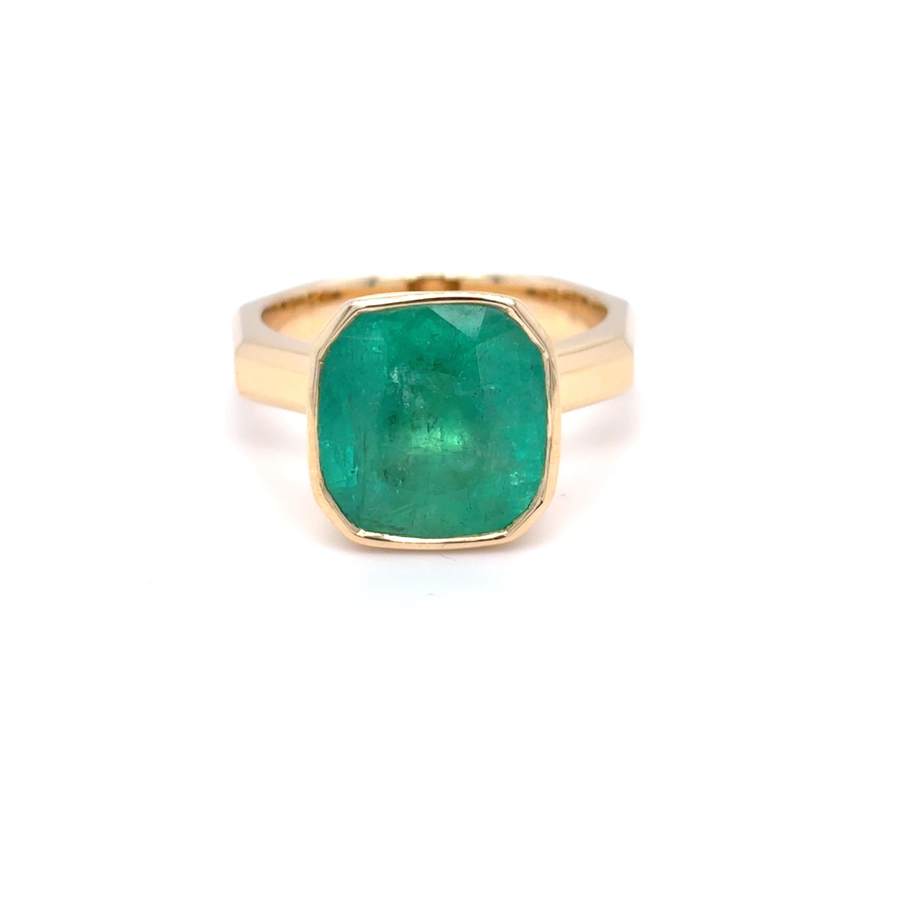 This exquisite 6.45-carat Colombian emerald ring features a cushion-brilliant cut, renowned for its rounded corners and larger facets that enhance brilliance and fire. Crafted in 14K yellow gold, the band is uniquely designed in an octagonal shape,