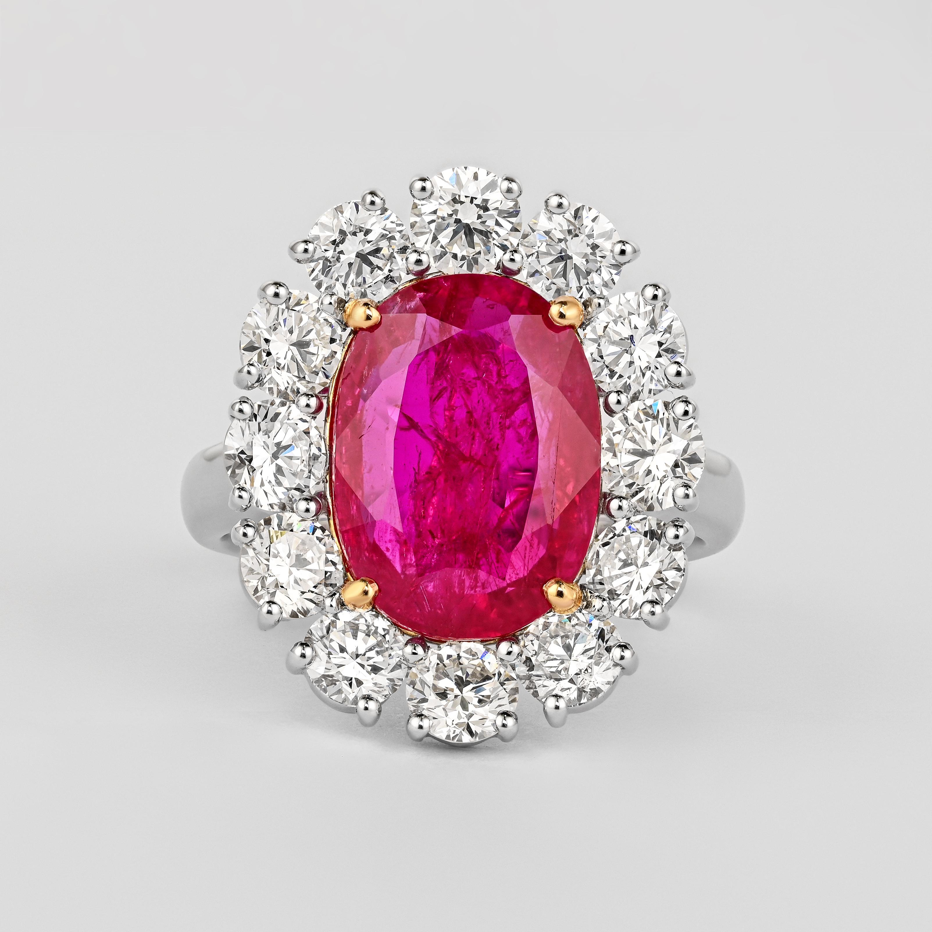 GRS Certified 6.45 carat unheated oval cut Ruby from Burma. Adorned with a diamond halo of 12 round cut white diamonds totaling 2.96 carats (0.25ct each). All set in a luxurious 18K white gold band with a floral basket mounting the center stone and